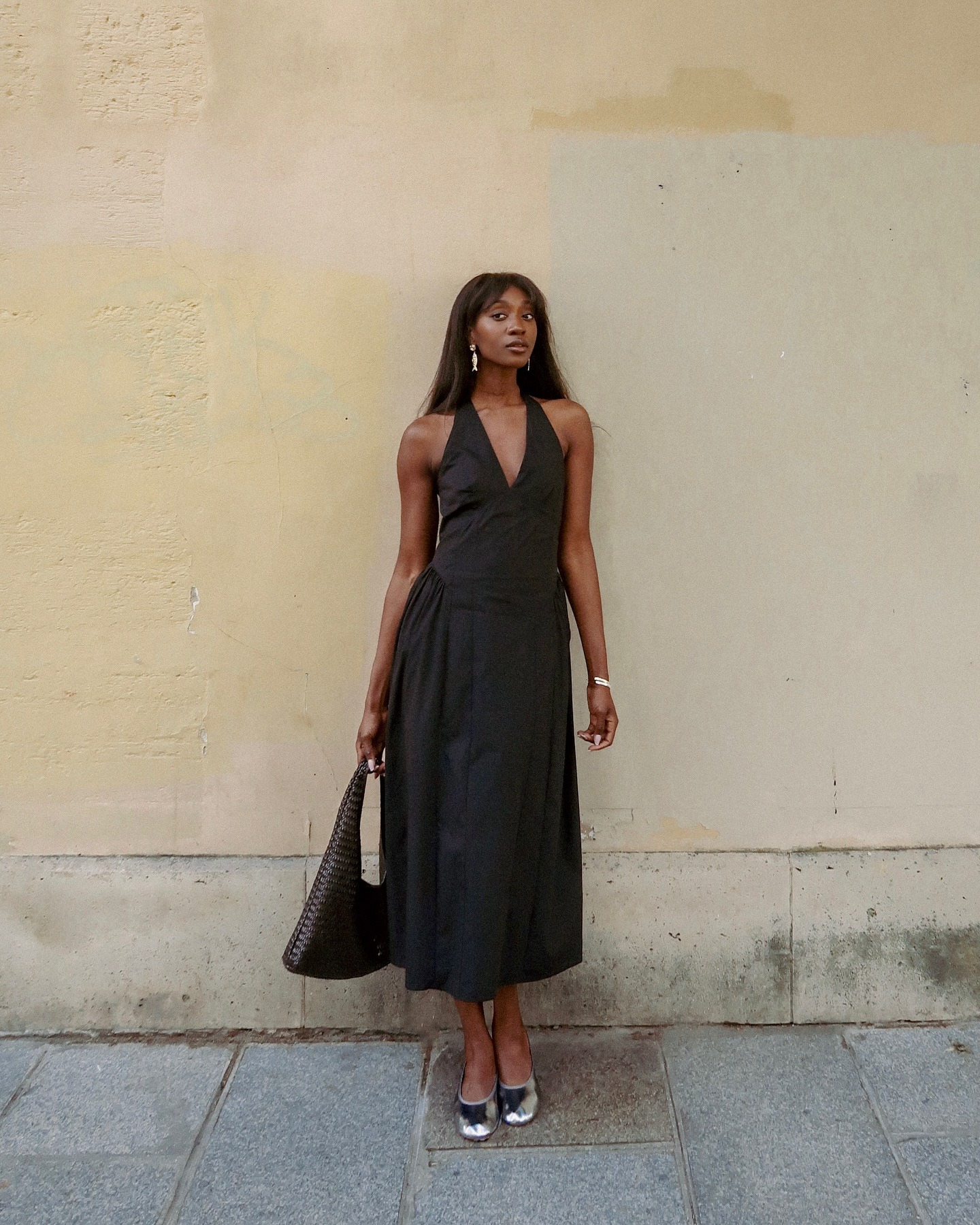 French influencer wearing a black halter dress and metallic shoes