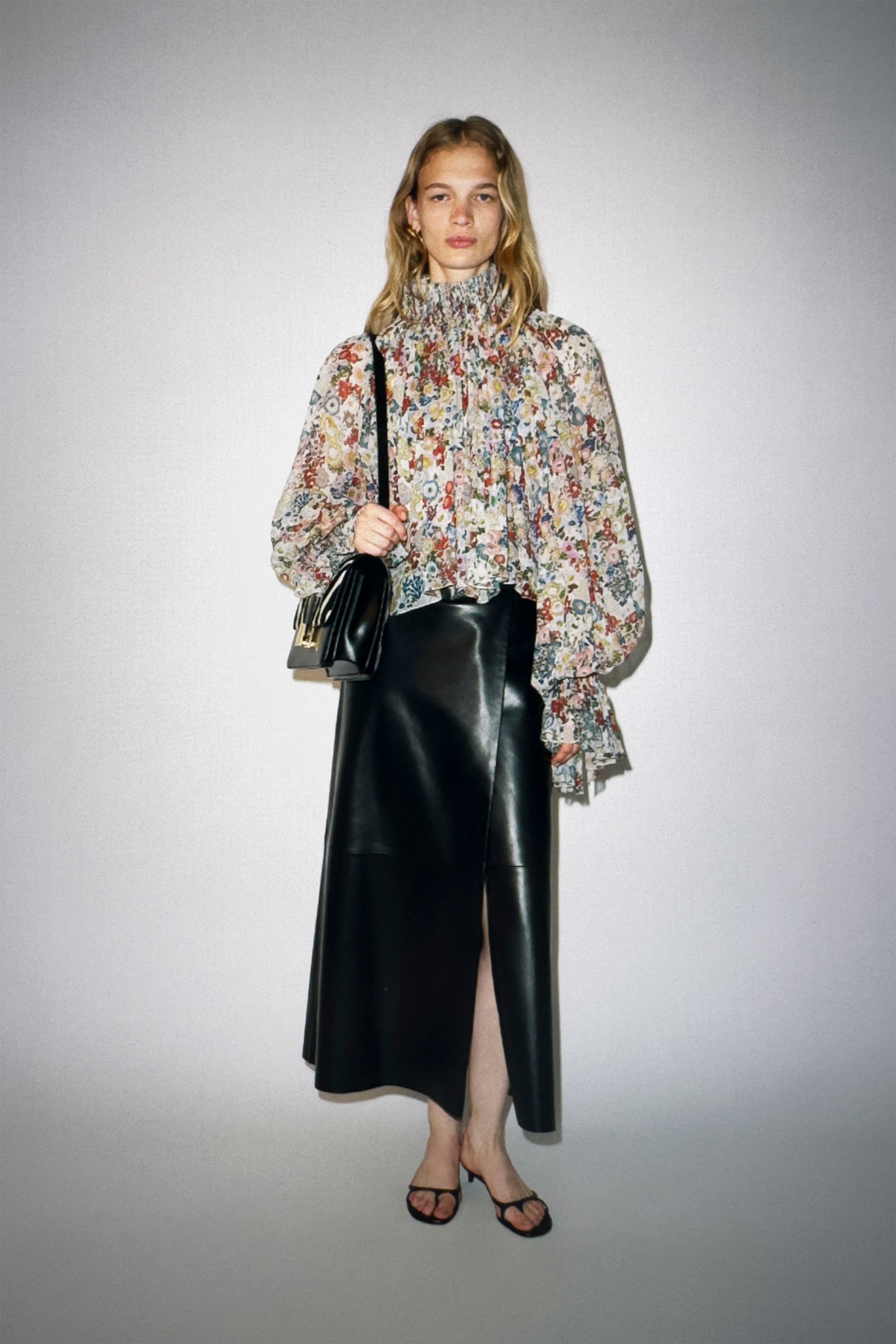 A Khaite model in the Resort 2026 lookbook wearing a floral boho blouse with a leather skirt and sandals. 