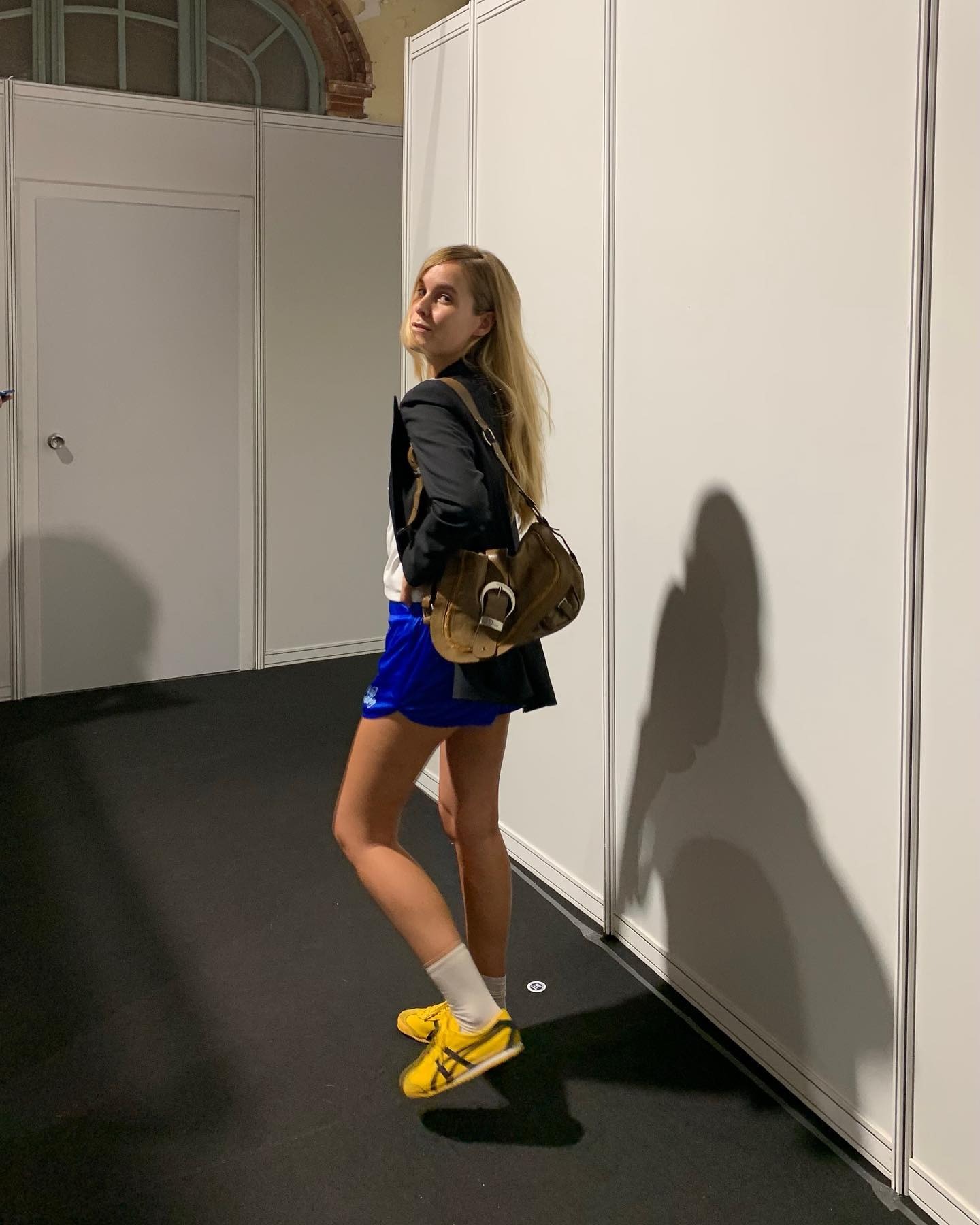 Lucia Cuesta wearing blue track shorts and yellow Onitsuka Tiger sneakers.