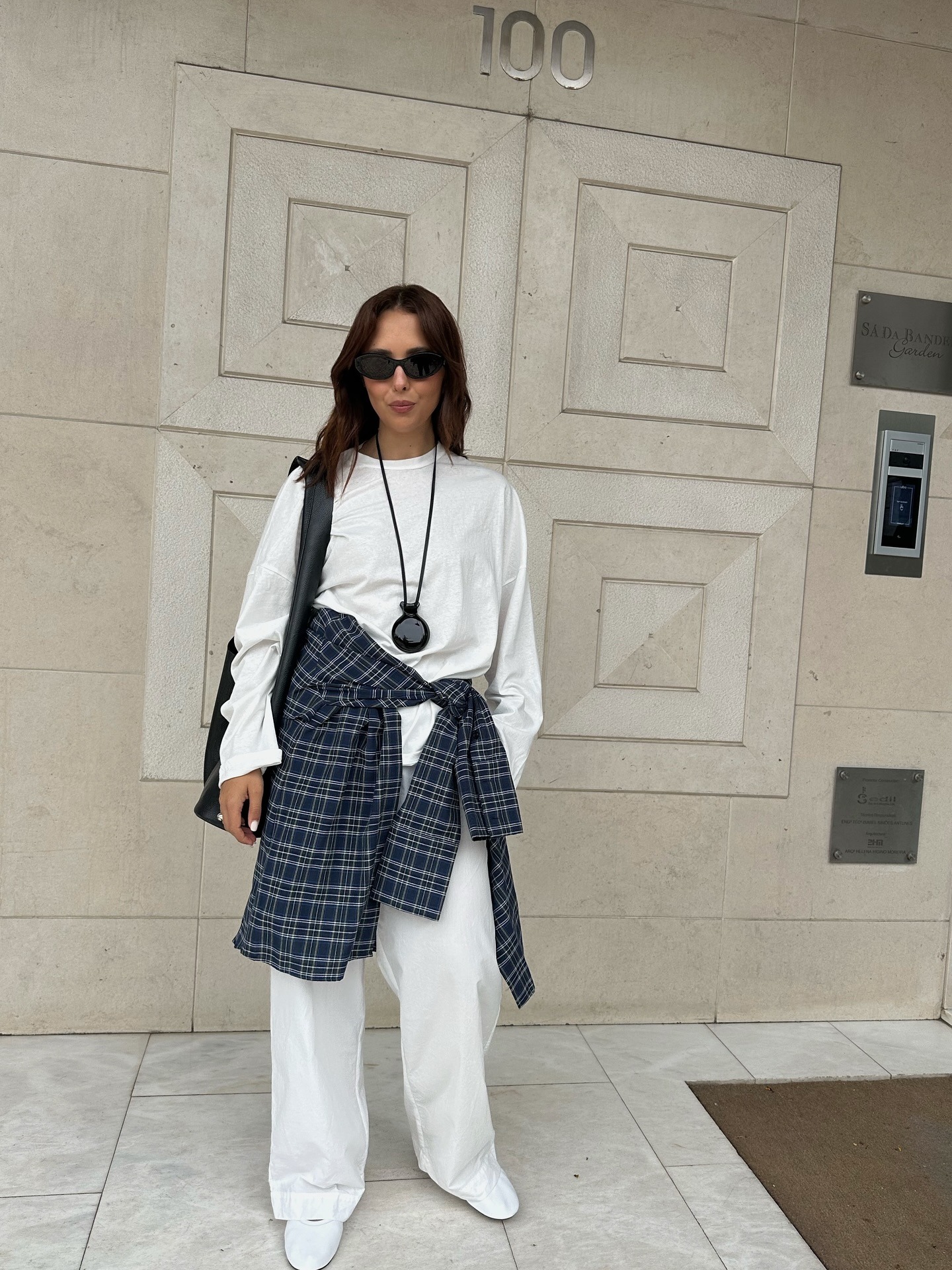 Debora Rosa wearing a white tee, white jeans, and a plaid shirt around her waist.