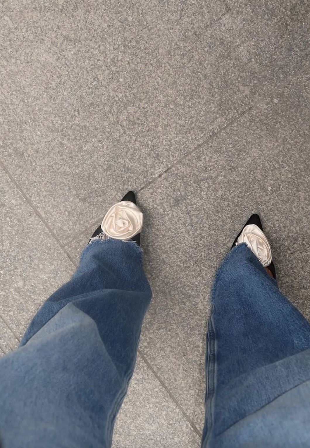 woman wearing pointed-toe heels with white roses and jeans
