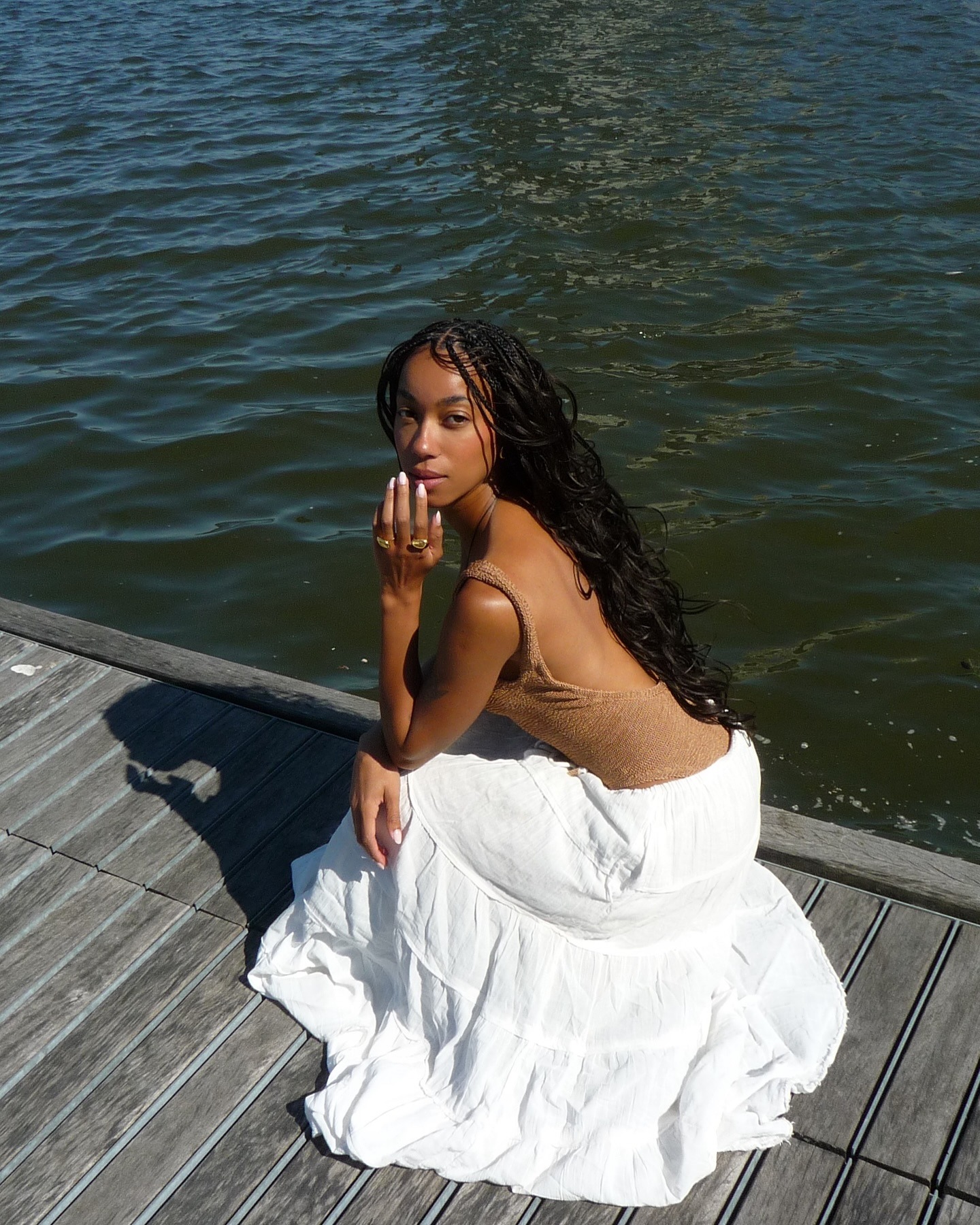 Influencer wearing a swimsuit and long white skirt.
