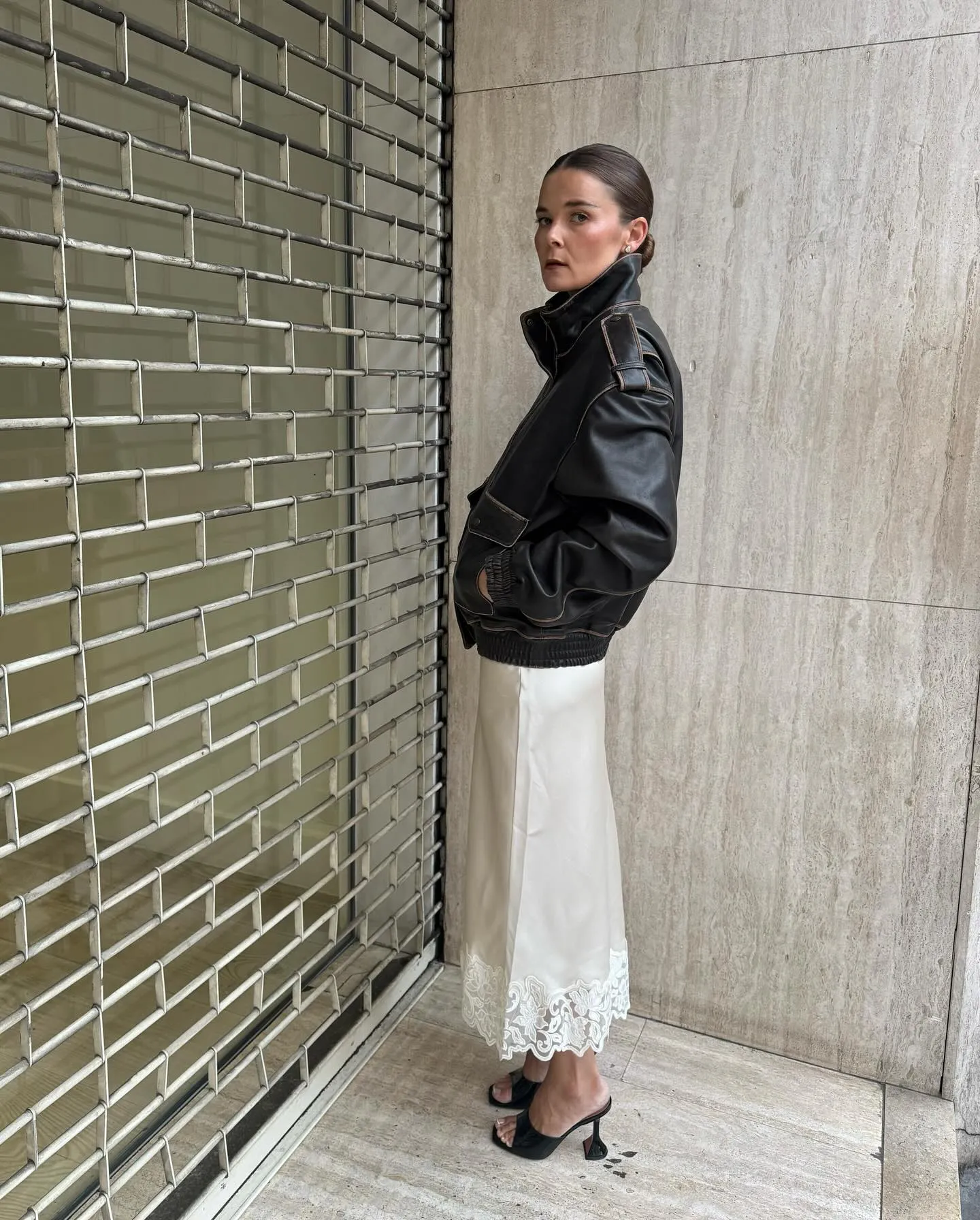 @rikkekrefting wearing black leather jacket, lace skirt, and black heels