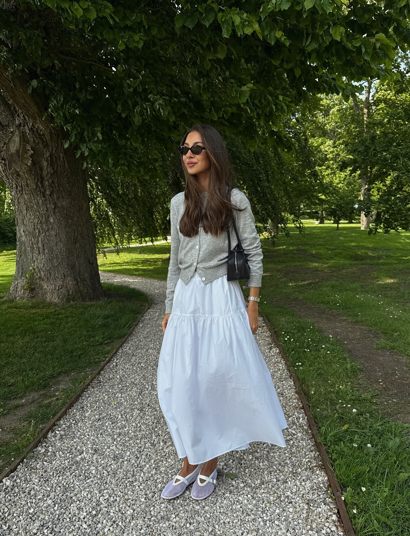 Influencer wearing a white midi skirt with a cardigan.