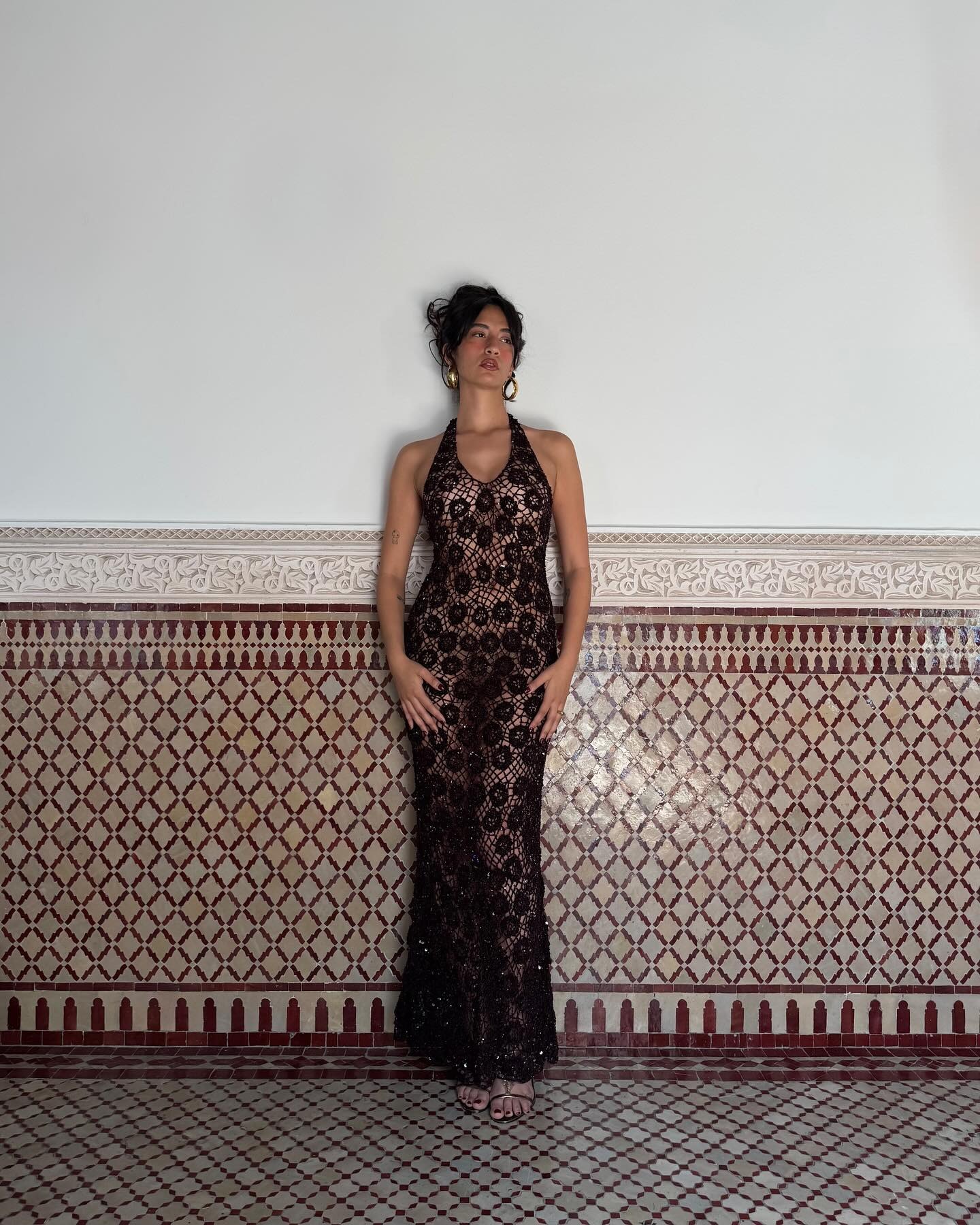 A woman wears a long black lace dress.