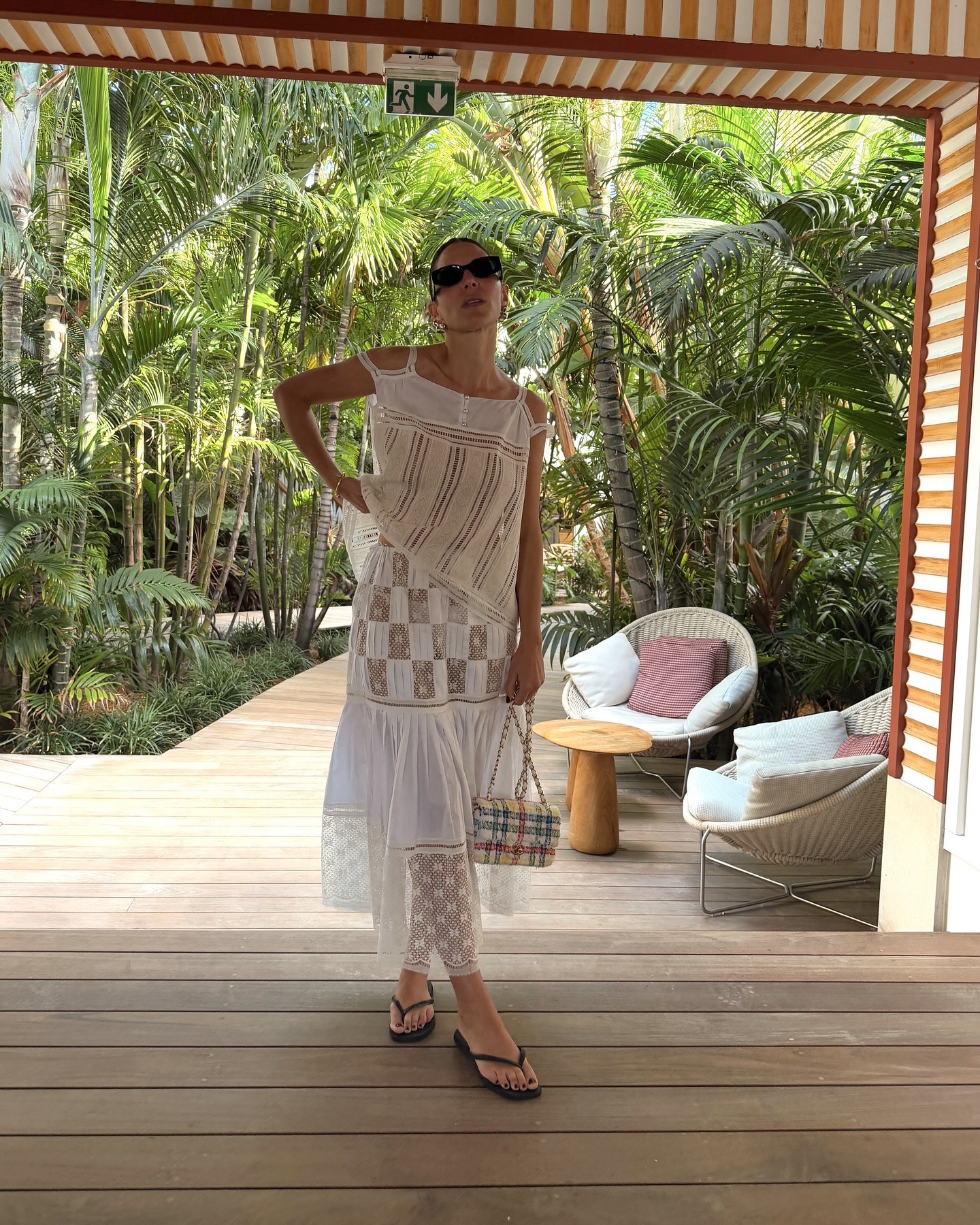 Jen wears a white lace top, skirt, black flip-flops and a Chanel bag.