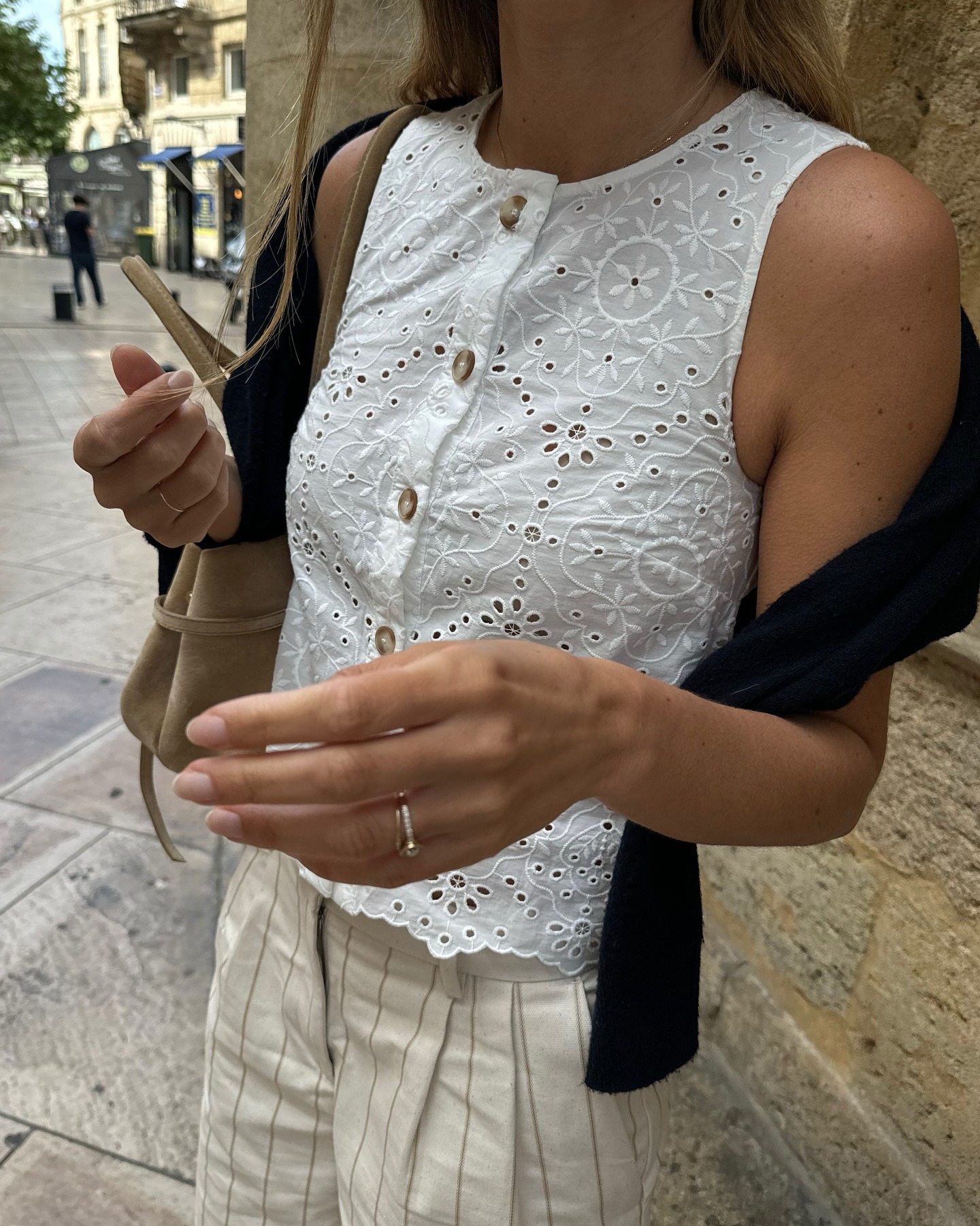 Influencer wearing a white eyelet top and striped pants.