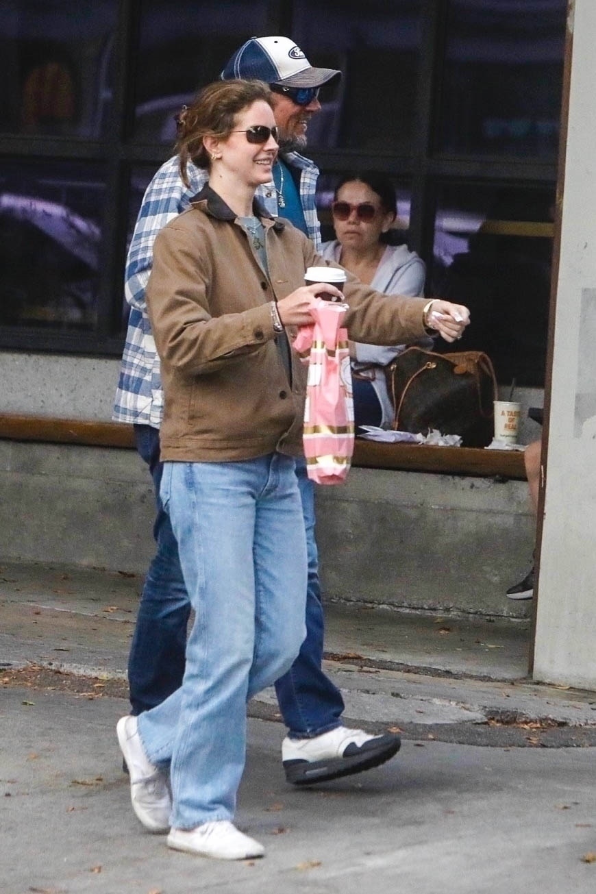 Lana Del Rey shopping in L.A. wearing a brown barn jacket, light-wash jeans, and white sneakers.