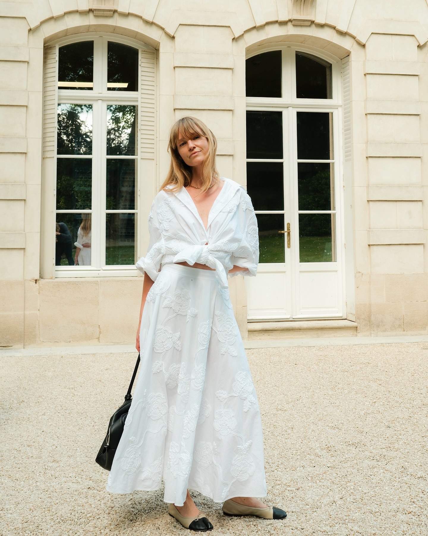 Influencer wearing a white button-down and long white skirt.