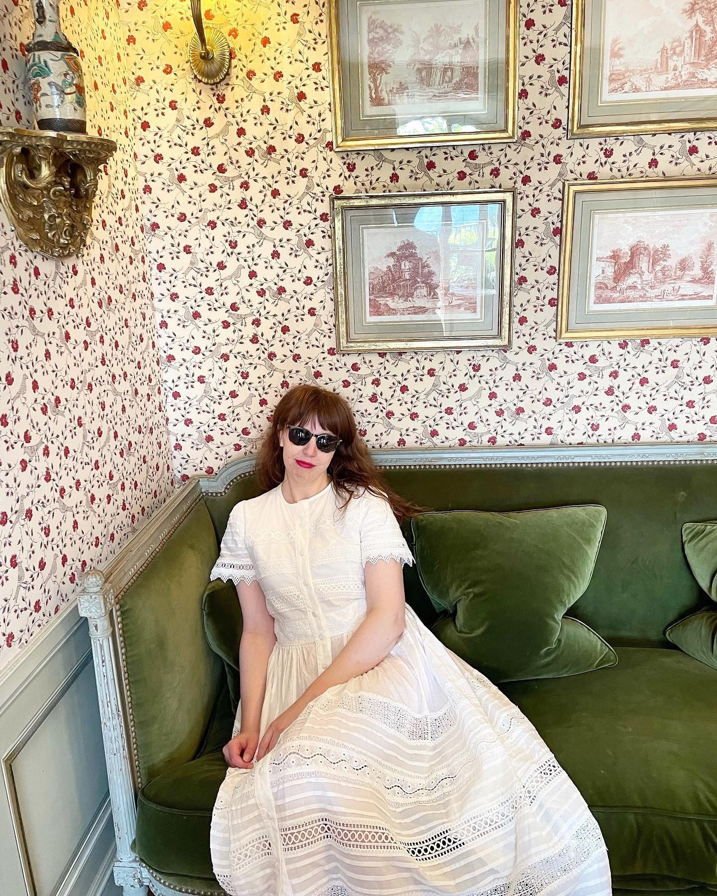 Erin wears a white maxi dress and black sunglasses.