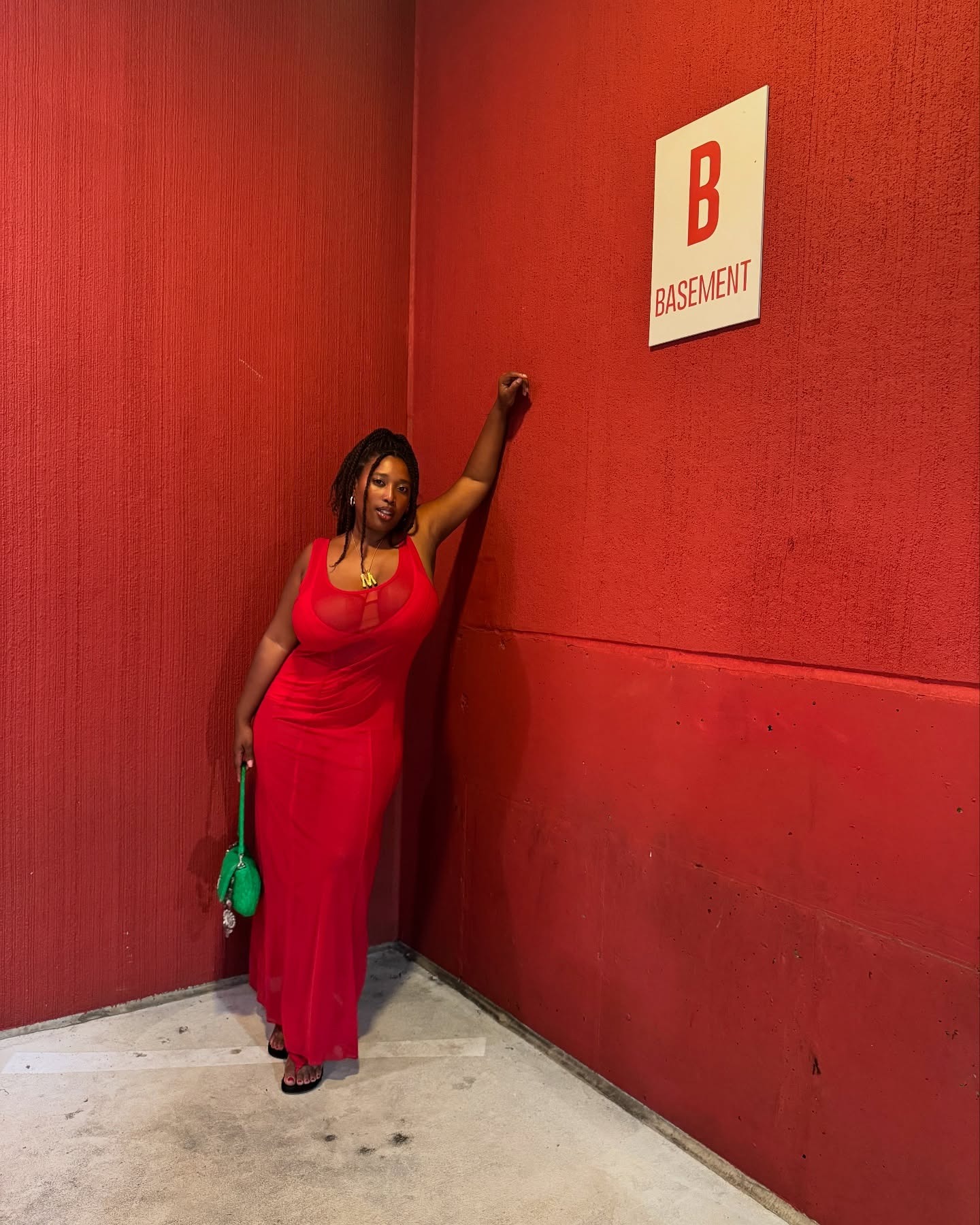 Mecca wears a red dress and green purse.