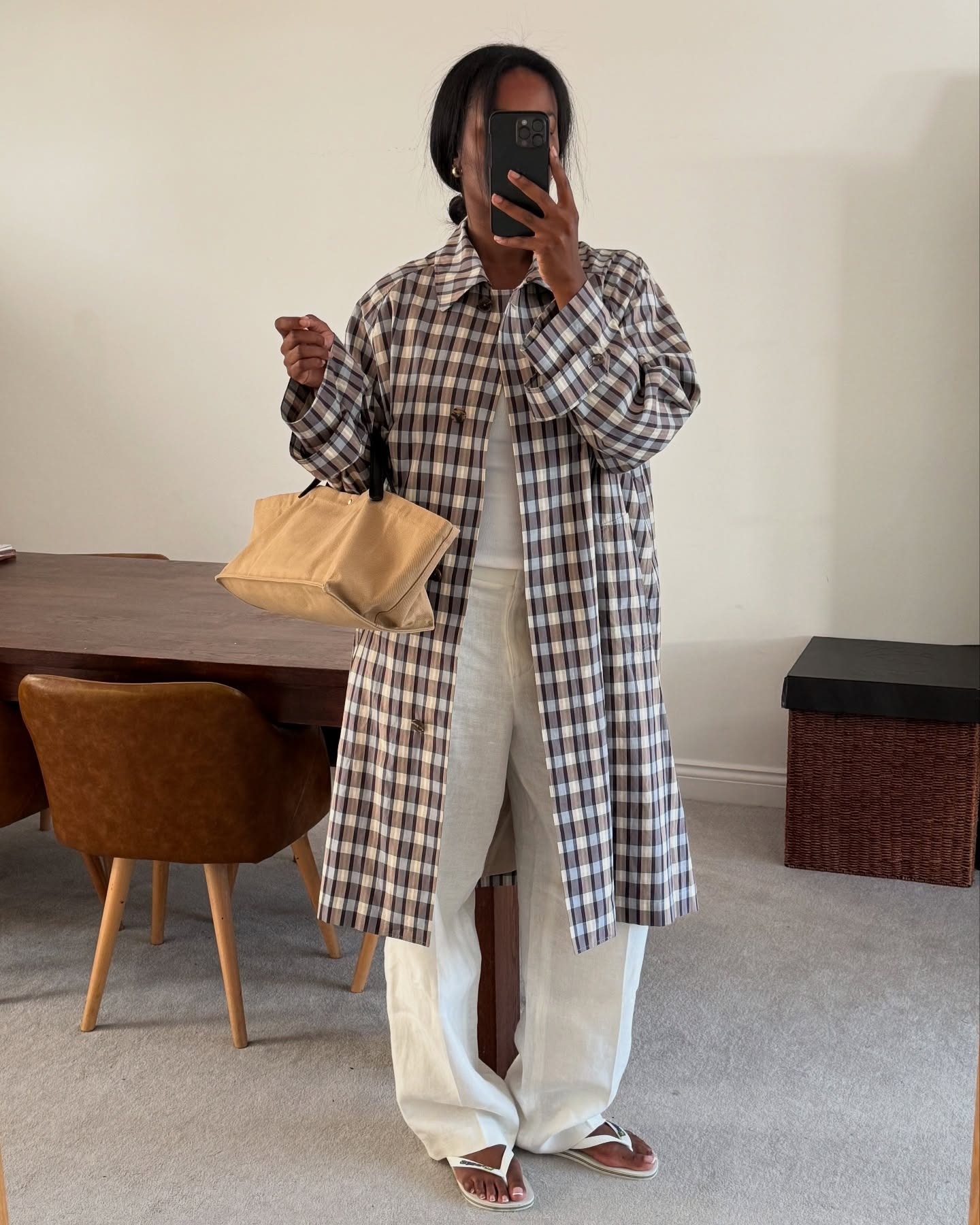 Influencer Marilyn NK wearing a checked trench coat and white pants with flip-flops.