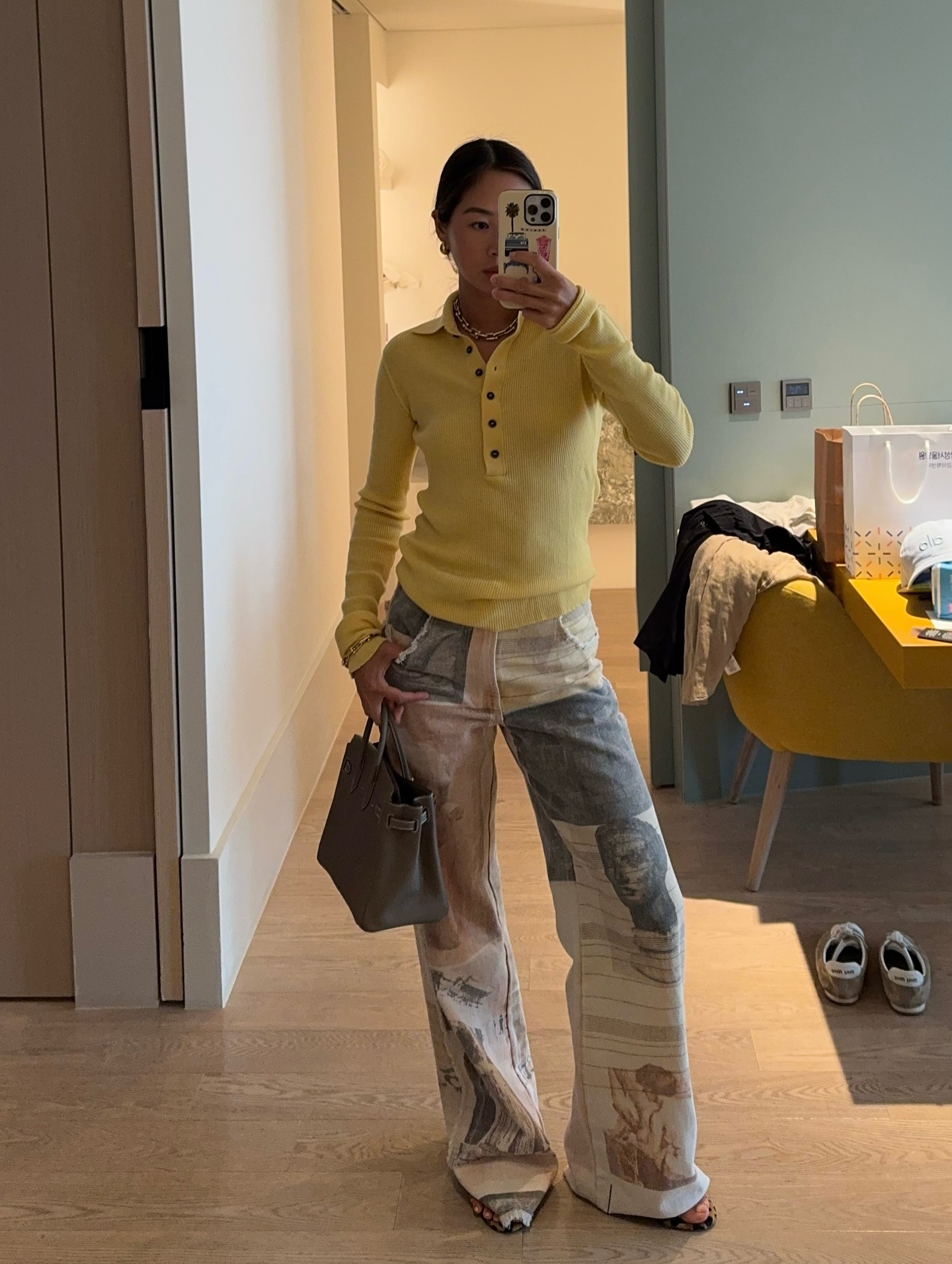 Influencer Aimee Song wearing a yellow polo sweater and printed jeans.