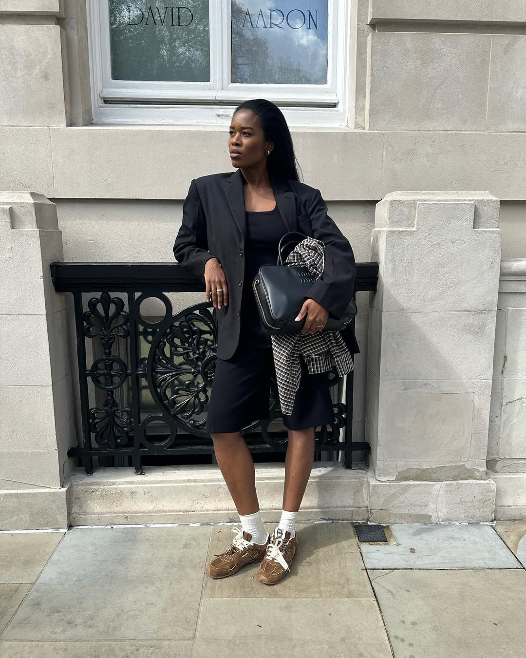 Influencer Marilyn wears suede sneakers, black shorts, blazer, and Miu Miu bag.