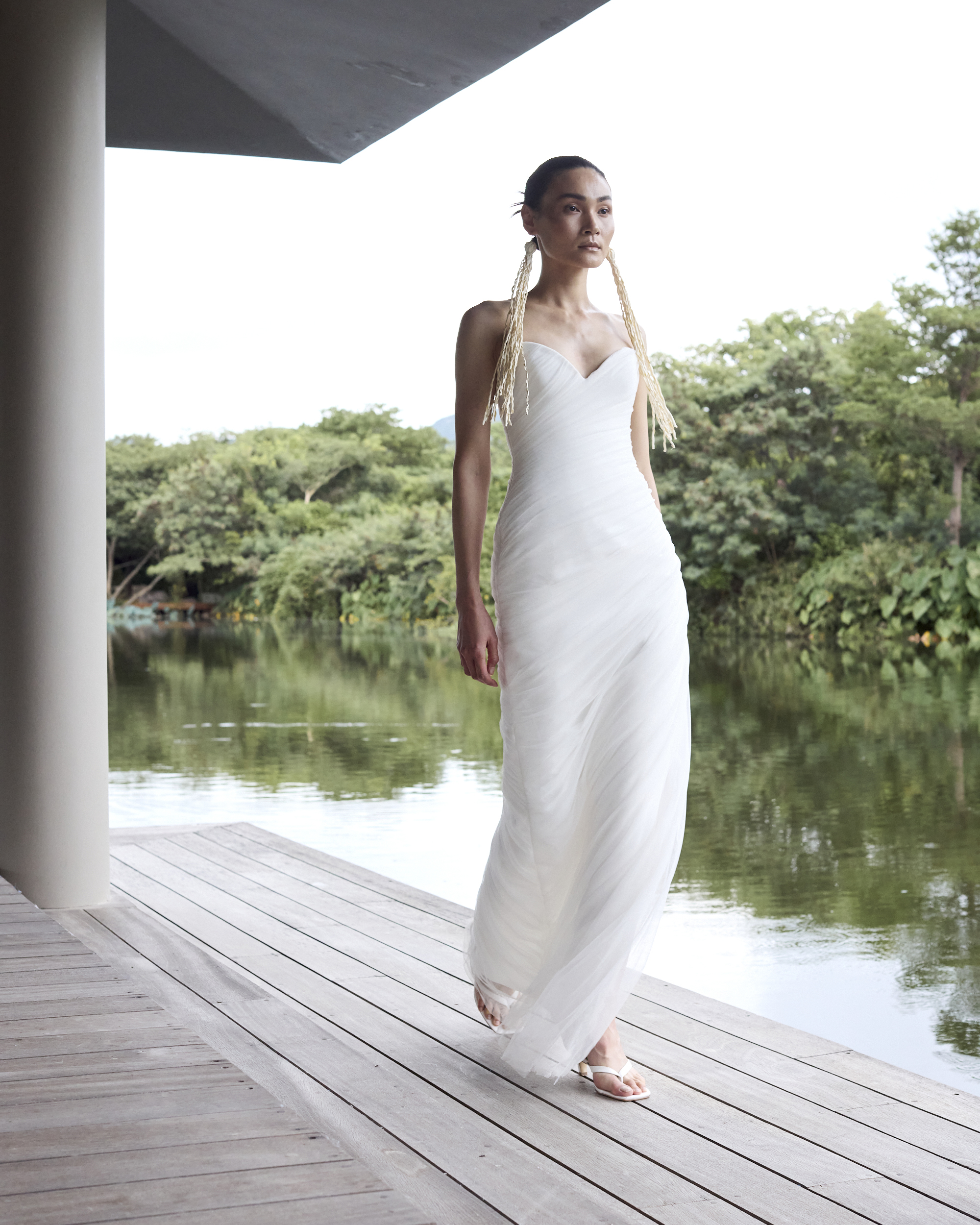 A woman wears a gown with a sweetheart neckline and long straw earrings.