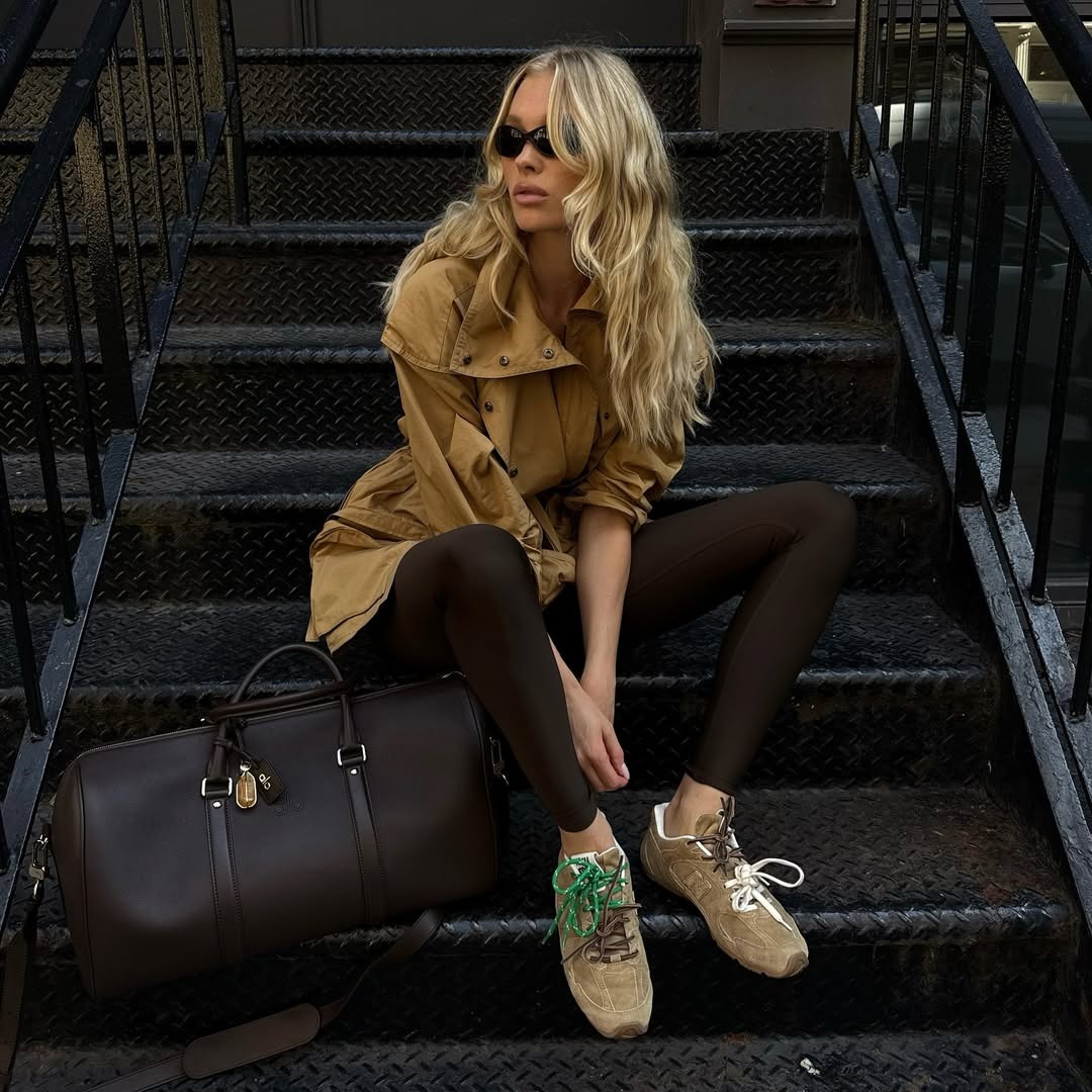 Elsa Hosk wears Alo bag with suede sneakers, brown leggings, and beige jacket.