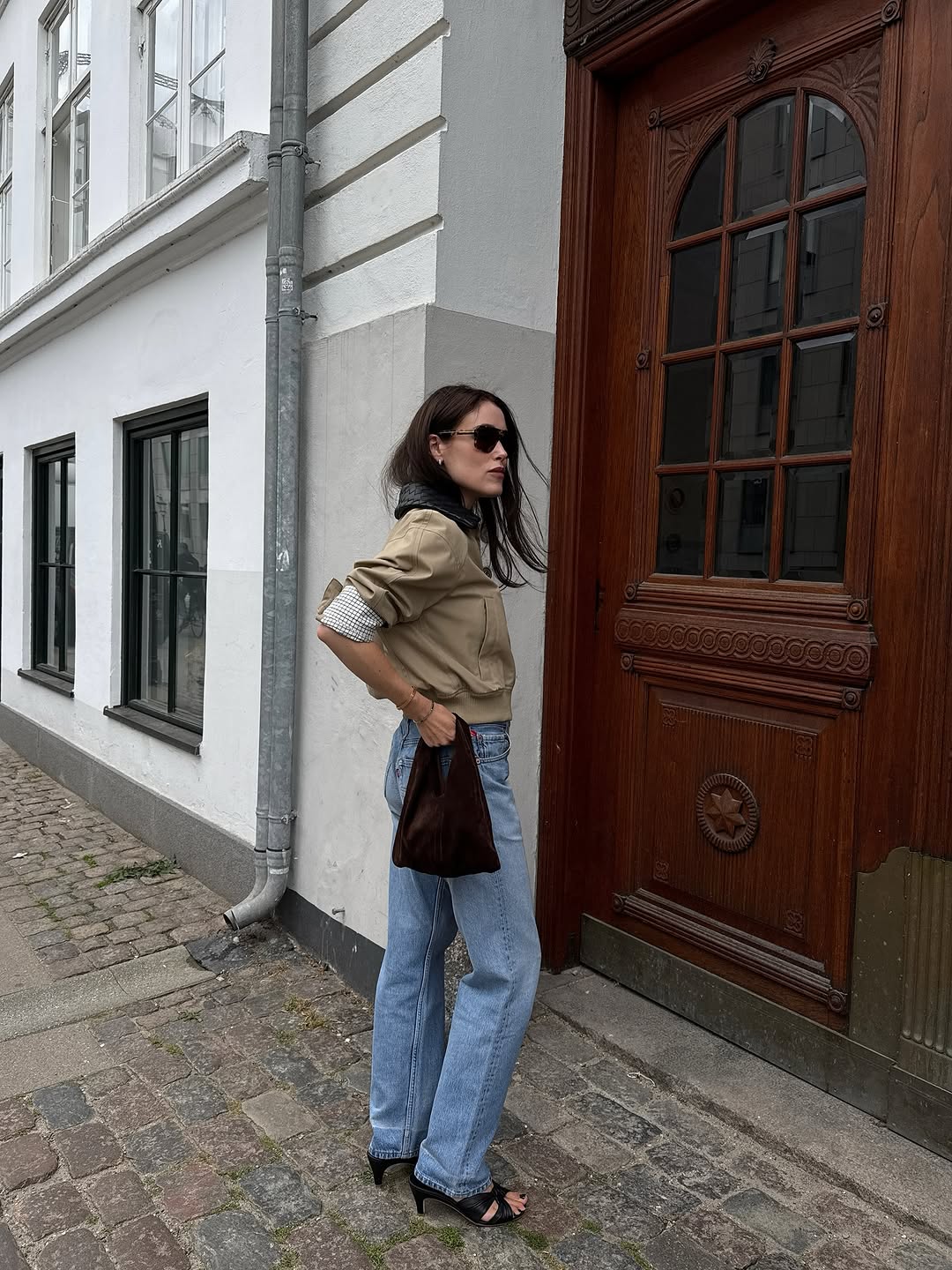 Woman wearing a tan jacket with jeans in a fall 2025 outfit.