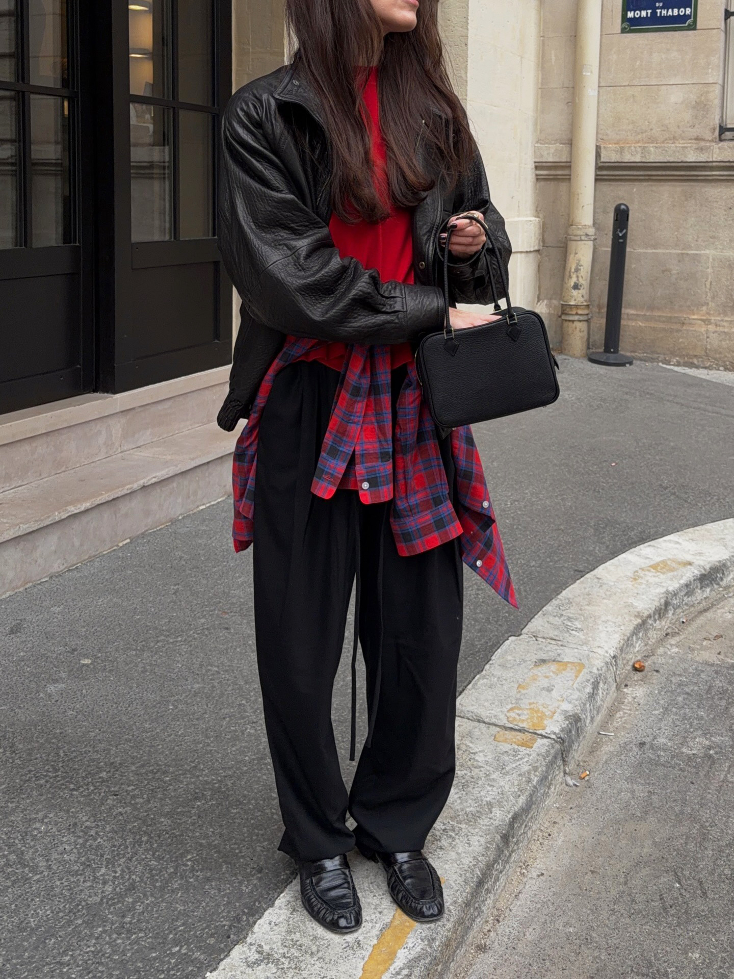 Influencer wearing a leather jacket, plaid shirt, black pants, and loafers