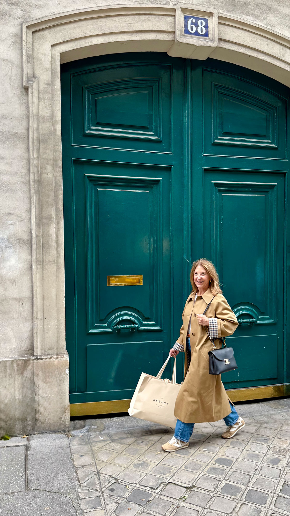 A Nordstrom stylist wearing a tan trench coat in Paris.