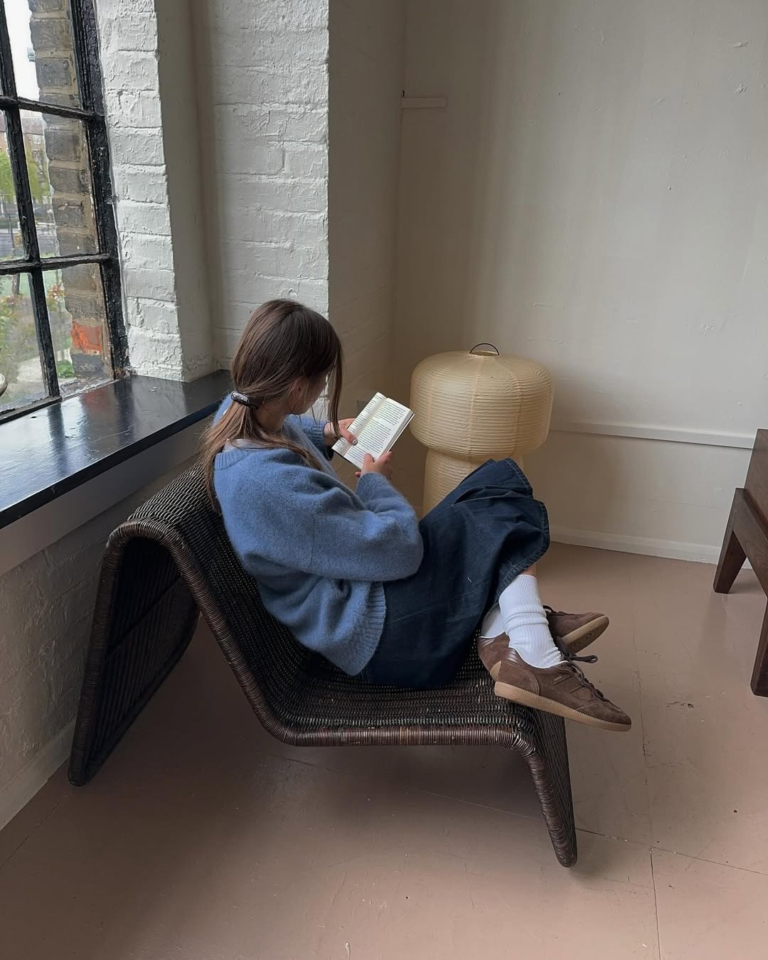 Influencer Poppy Almond wears a denim skirt, suede sneakers, and a blue sweater.