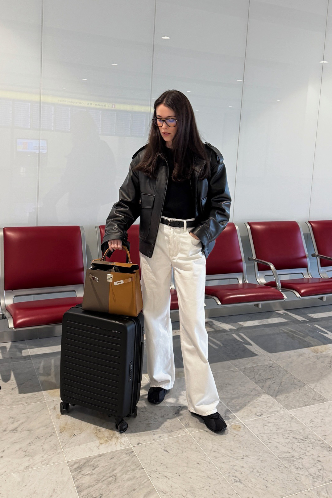 Influencer wearing a black leather bomber jacket and cream jeans at the airport