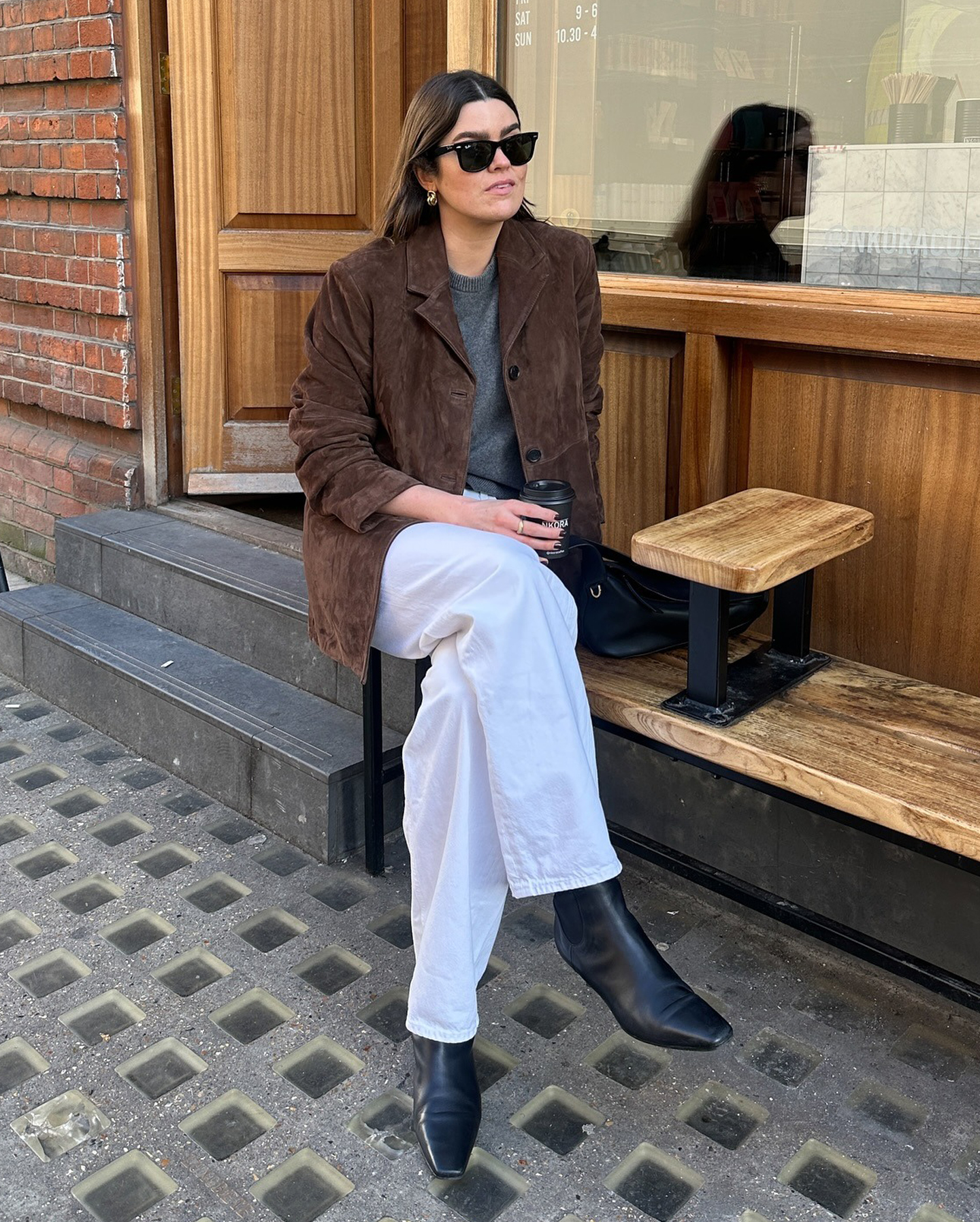 European style influencer Anna Newton wearing chic fall outfit with white jeans, a brown suede jacket, gray sweater, and square toe kitten heel boots