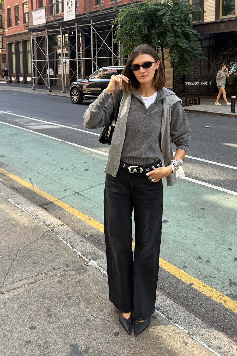 Influencer wearing a gray polo sweater, studded belt, and black jeans