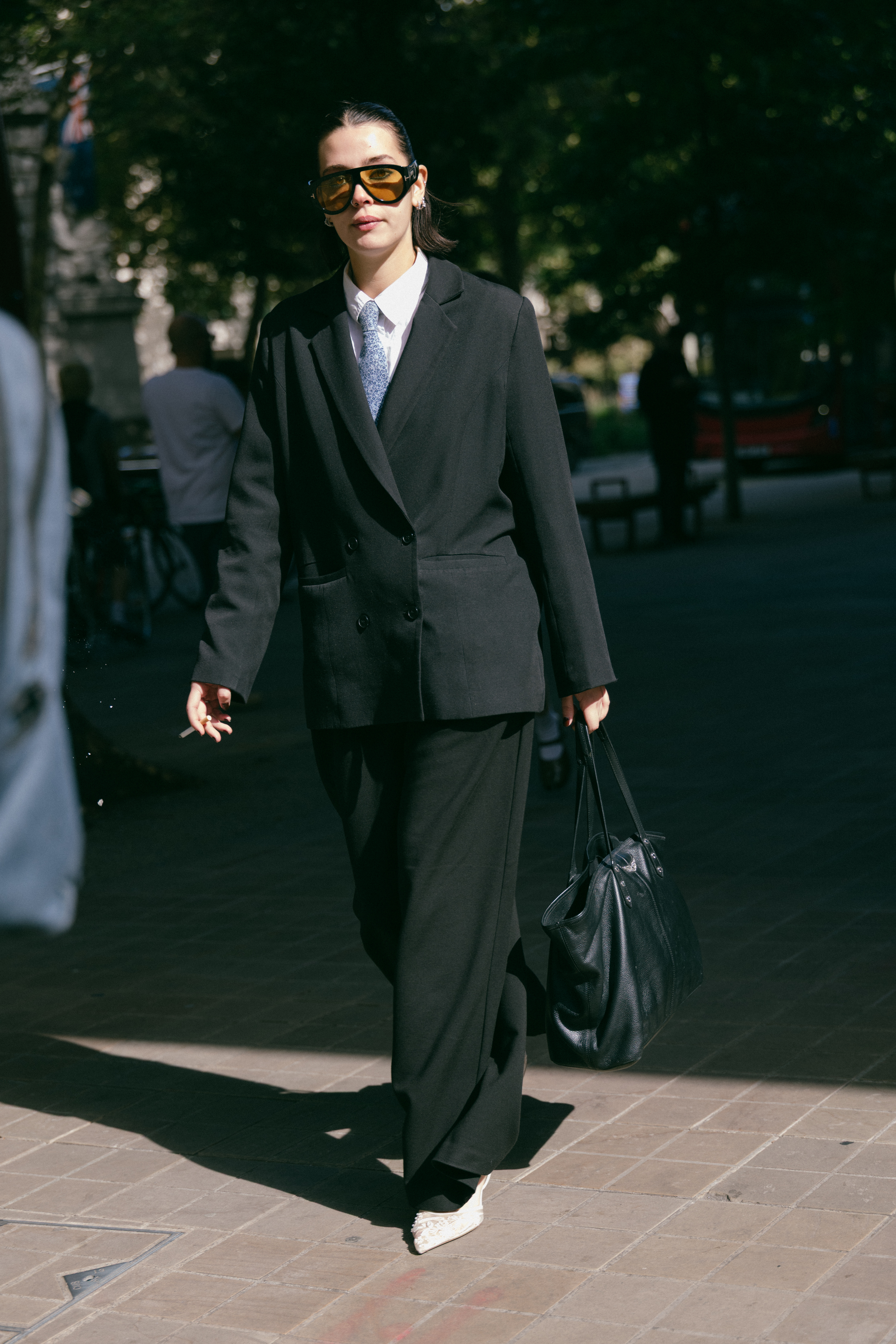 A woman wearing a black suit and white heels