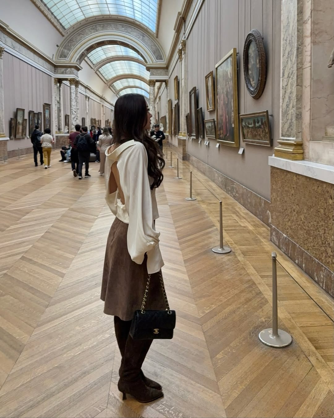 Influencer Zarayna Ferguson wears brown suede knee-high boots with a suede skirt, and silk white blouse.