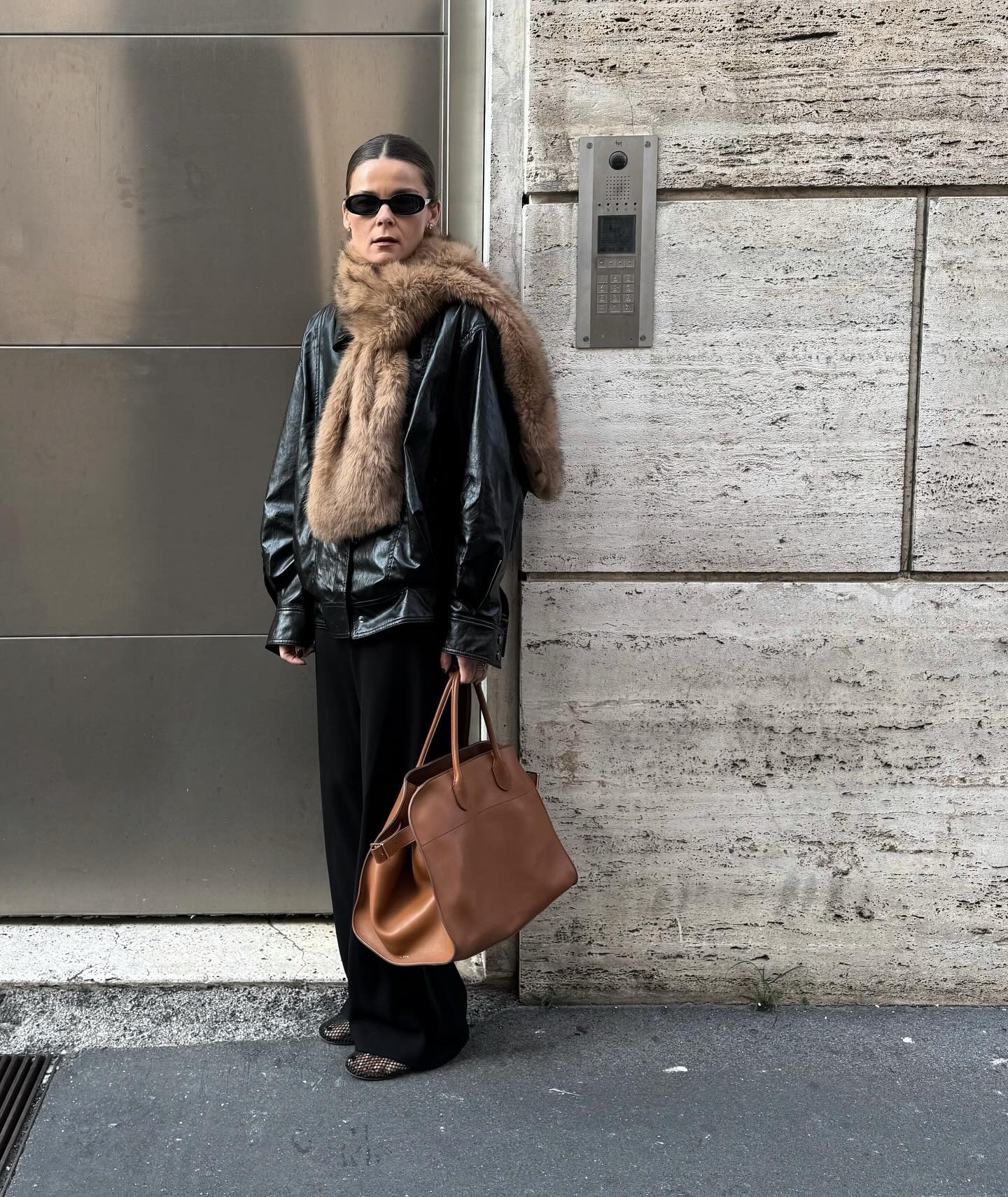 A woman wears a faux fur scarf with a coat and pants.