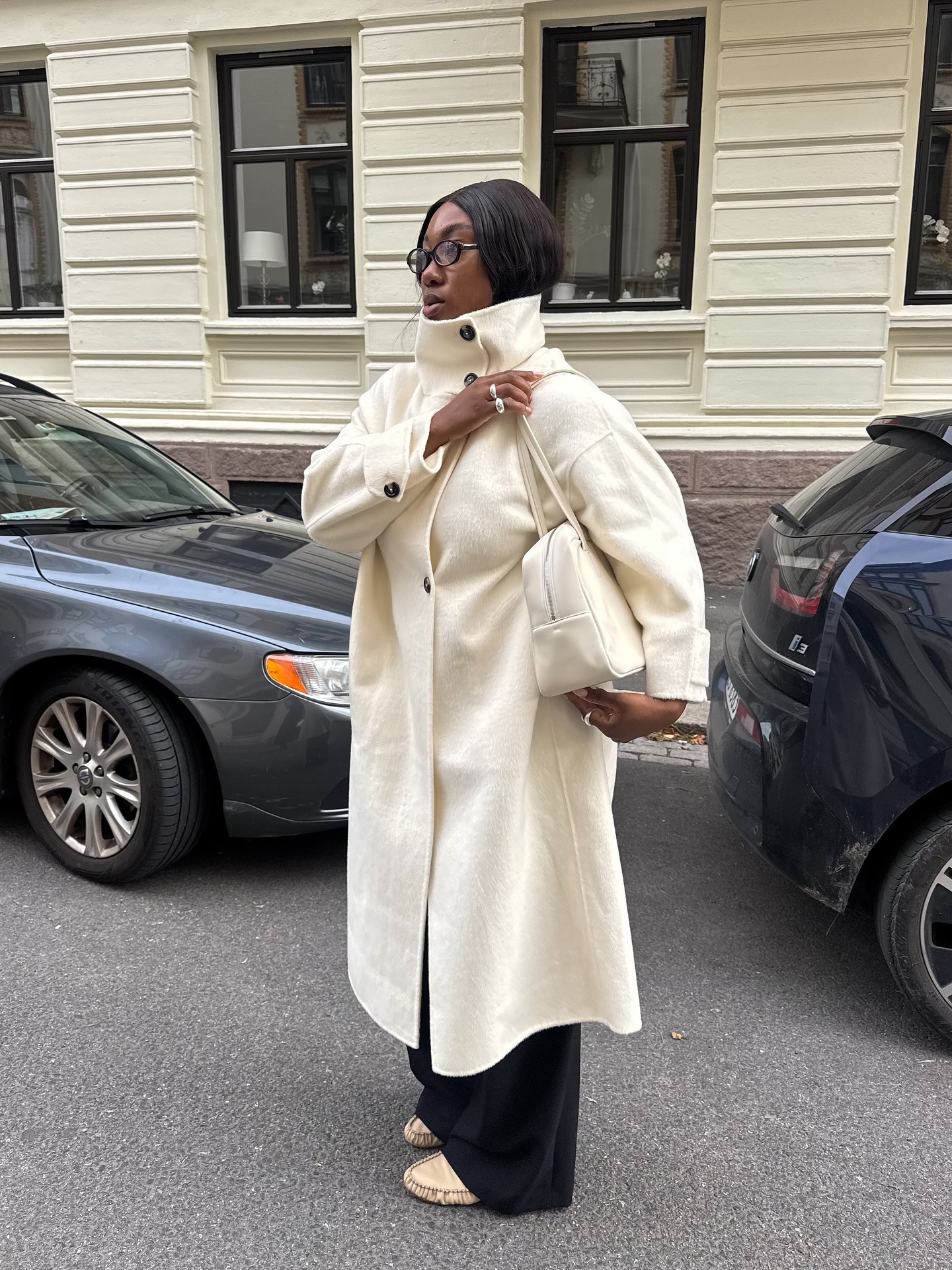 Influencer Nnenna wears a white funnel-neck coat.