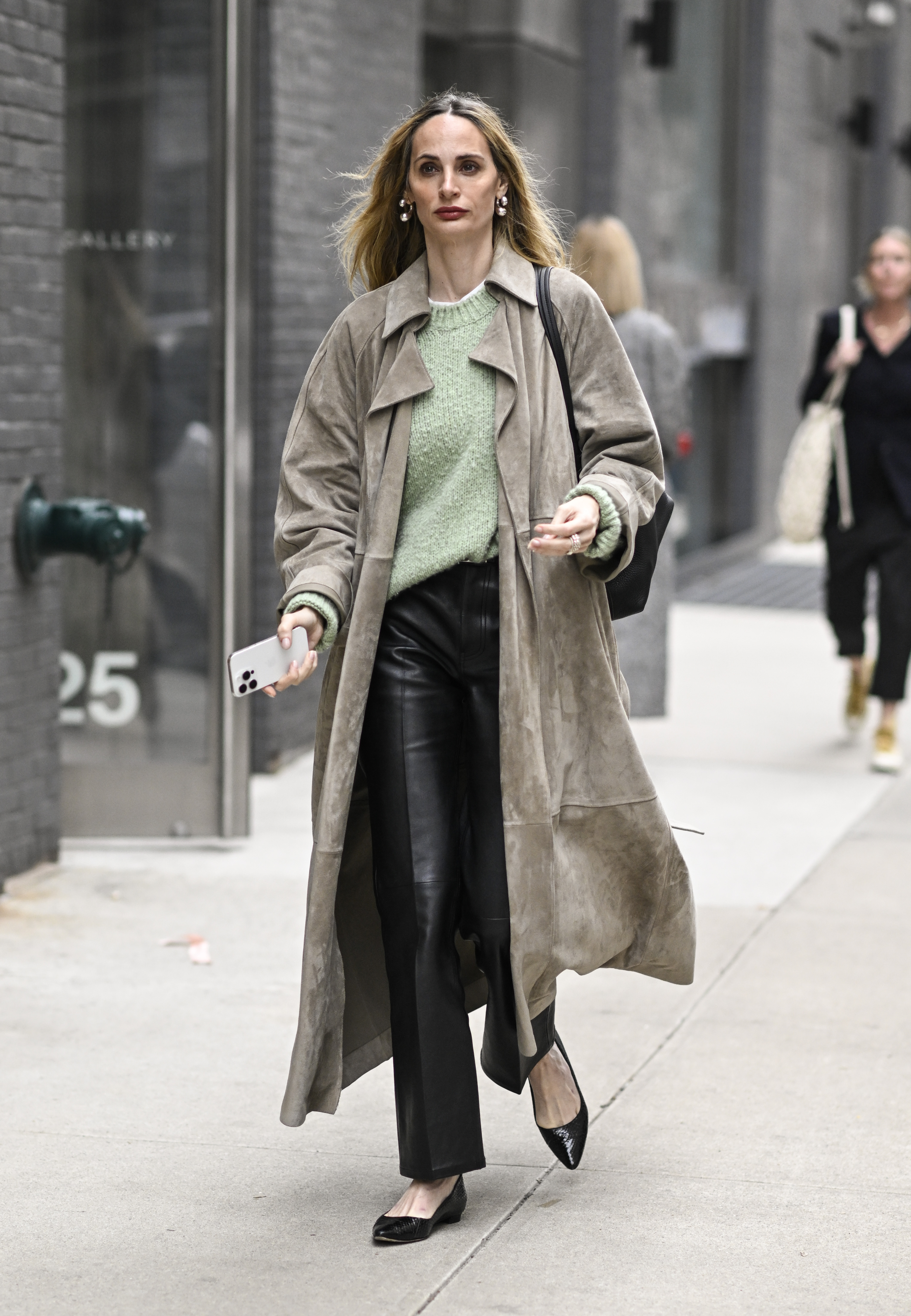 A woman wears a suede jacket, t-shirt, black leather pants, flats