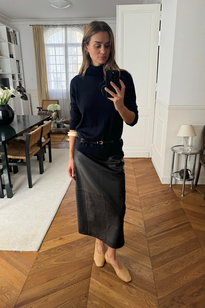 A woman wearing a black sweater and black leather skirt
