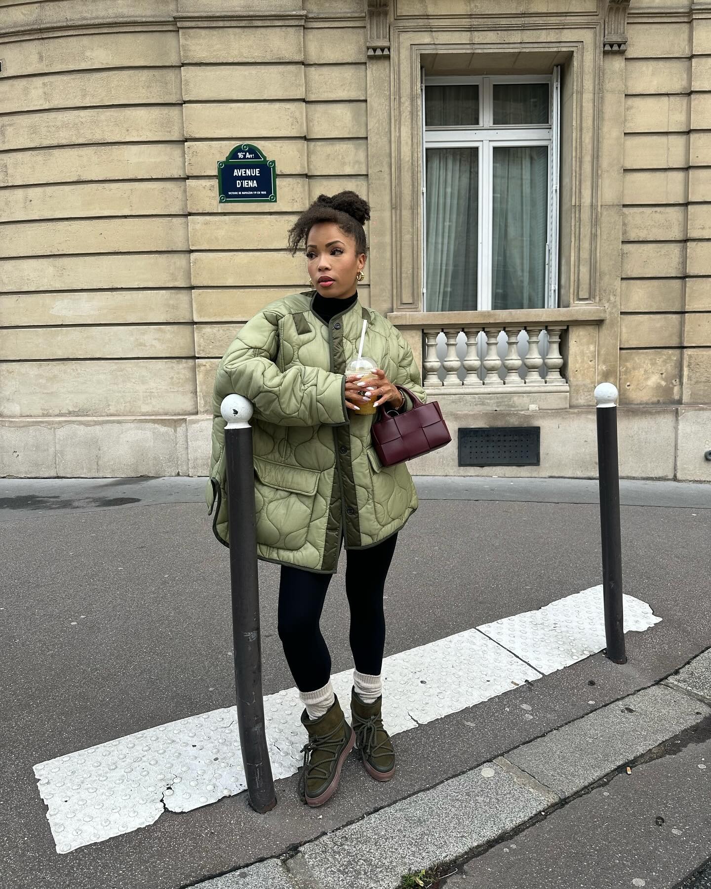 A woman wears a green coat, leggings, white socks, and green winter boots.