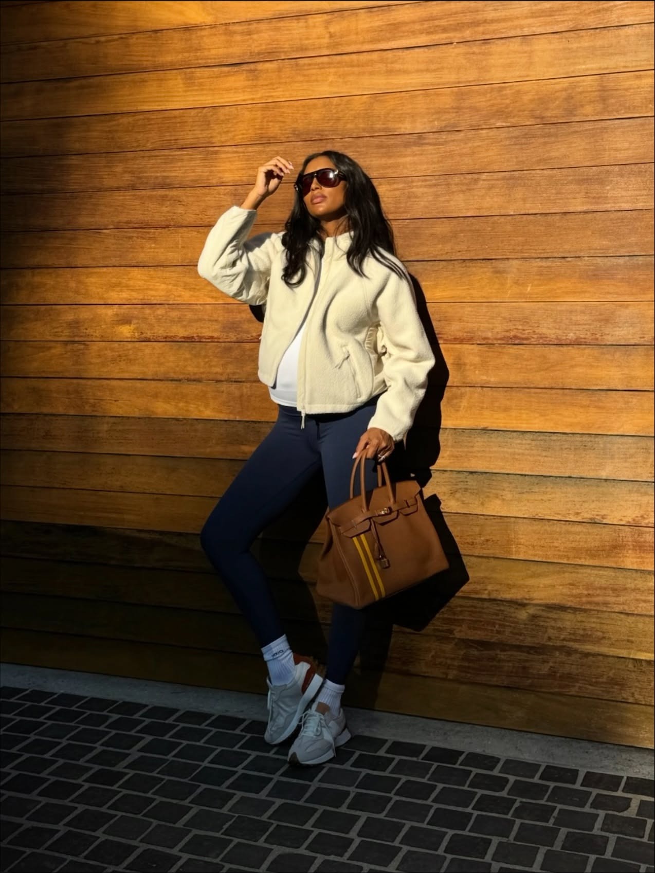 Jasmine Tookes wearing a cream jacket with navy blue leggings with white sneakers.
