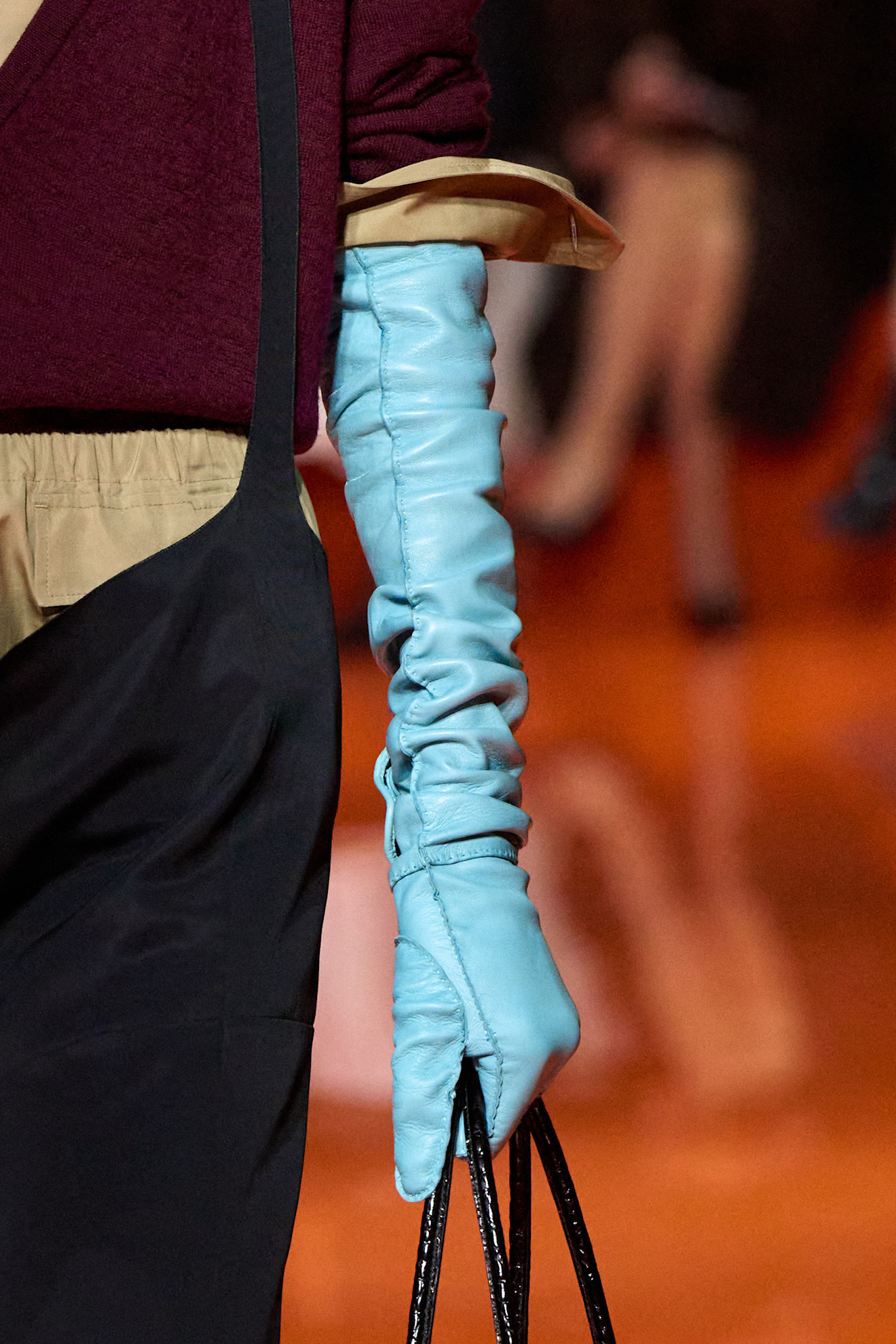 Model wearing colored gloves on the runway.