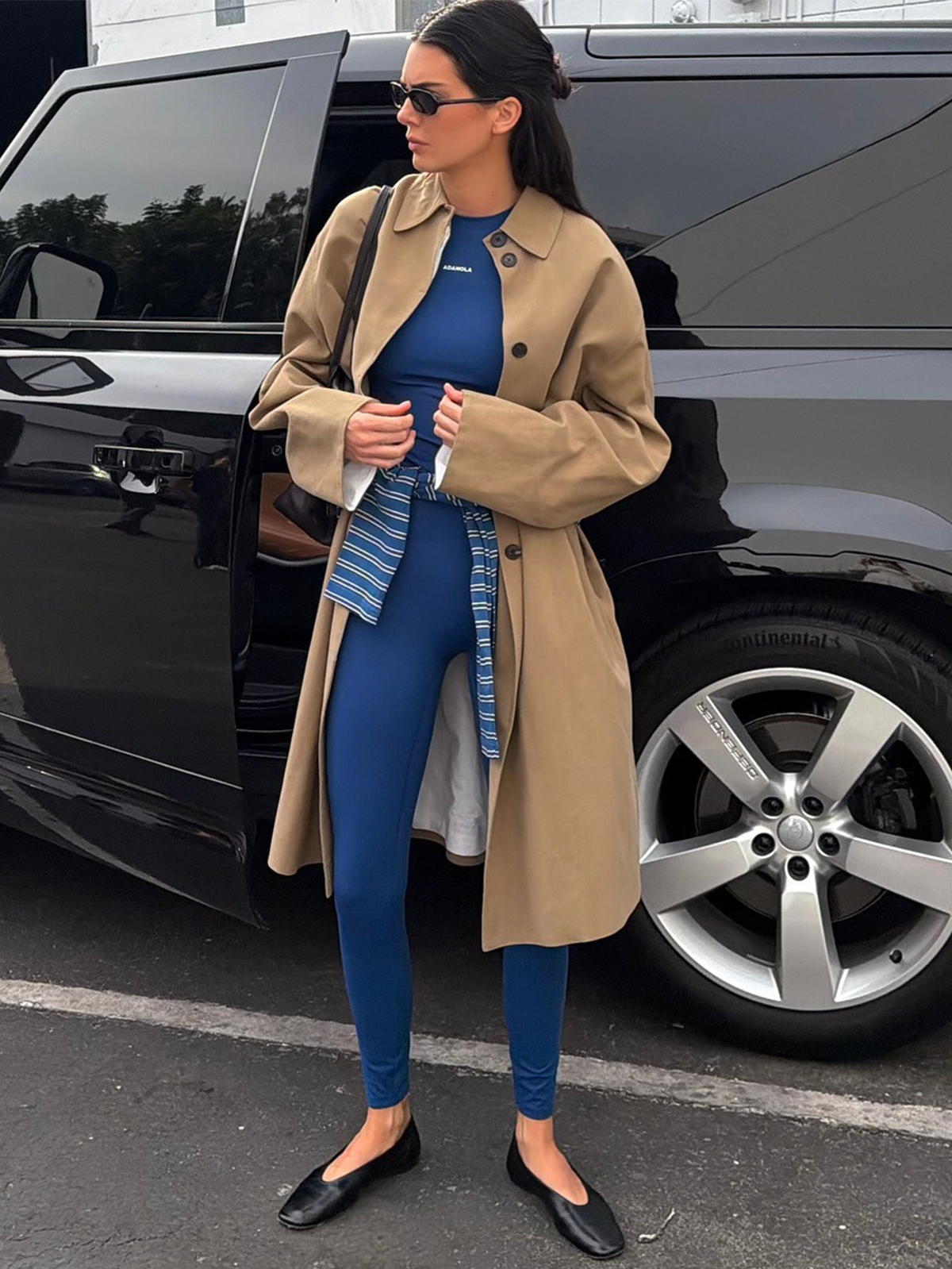 Kendall Jenner wearing blue leggings and a matching bra with a khaki car coat.