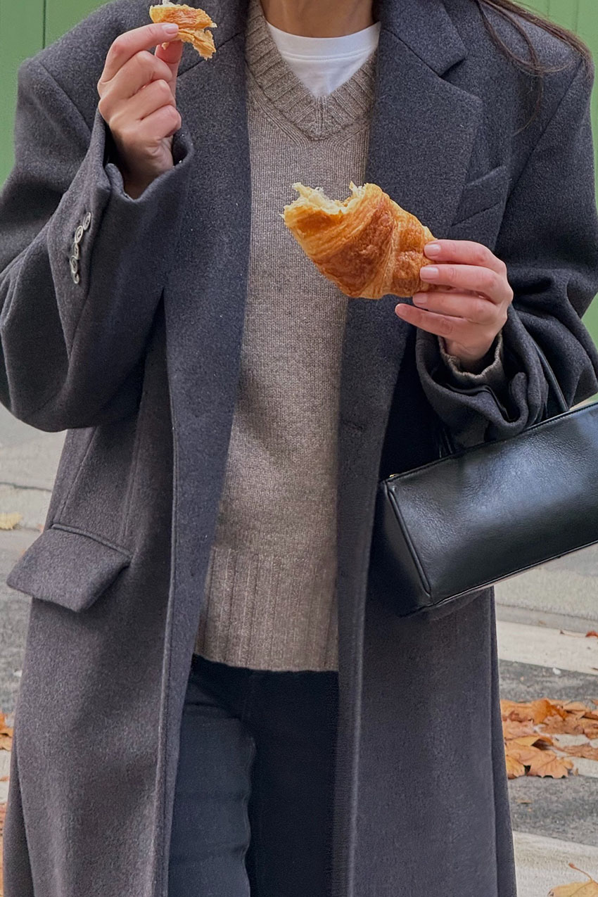 a woman wearing a gray wool coat and beige sweater