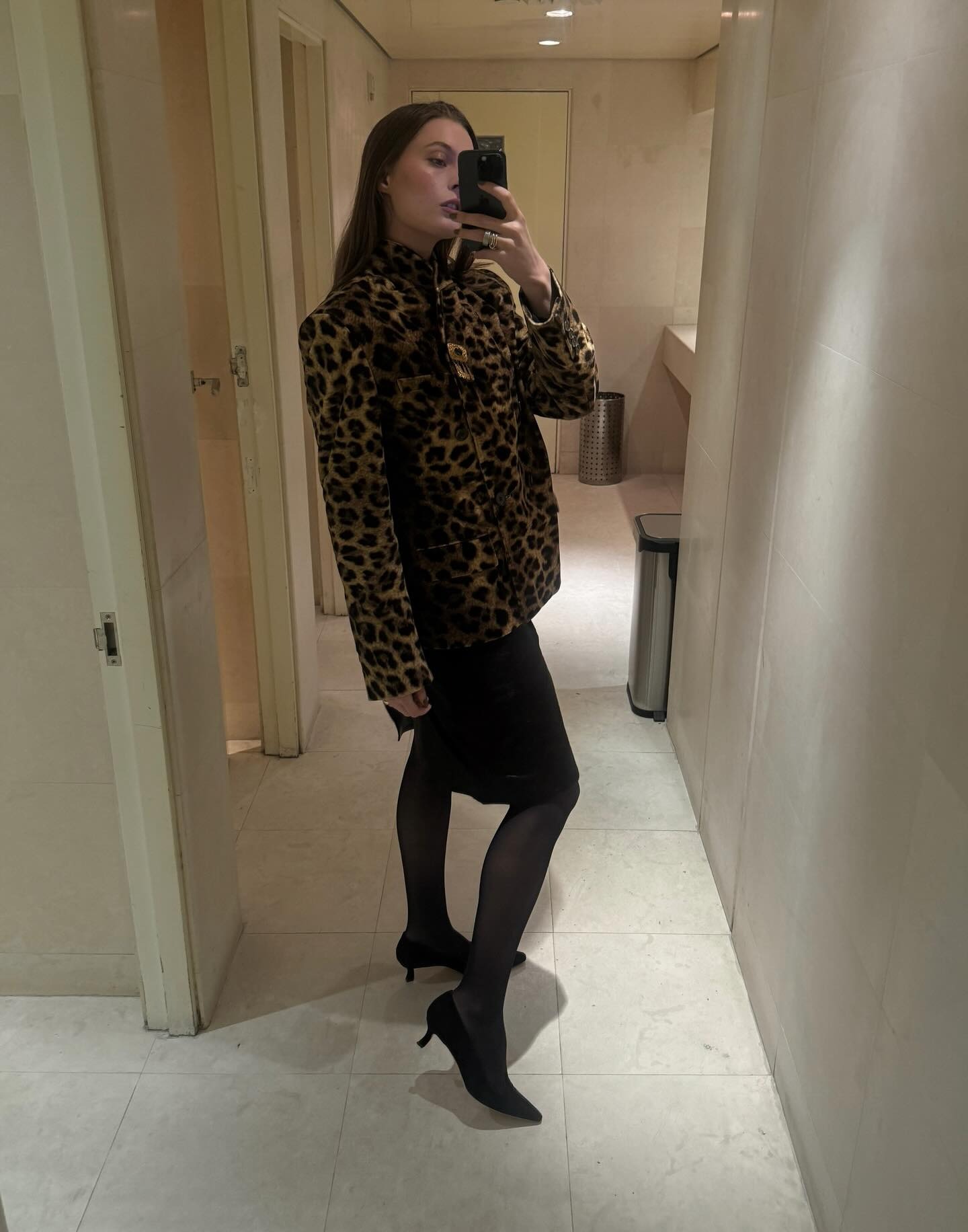 Christie wears a leopard coat, black pencil skirt, and black pumps.