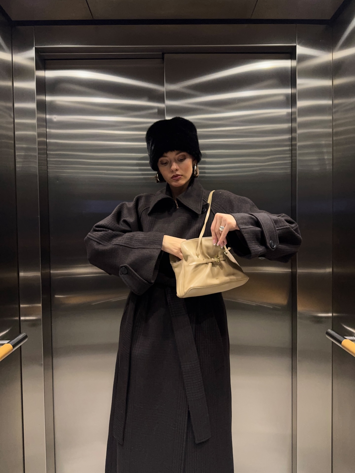 @maryljean wearing a long brown belted coat and the faux-fur hat trend.