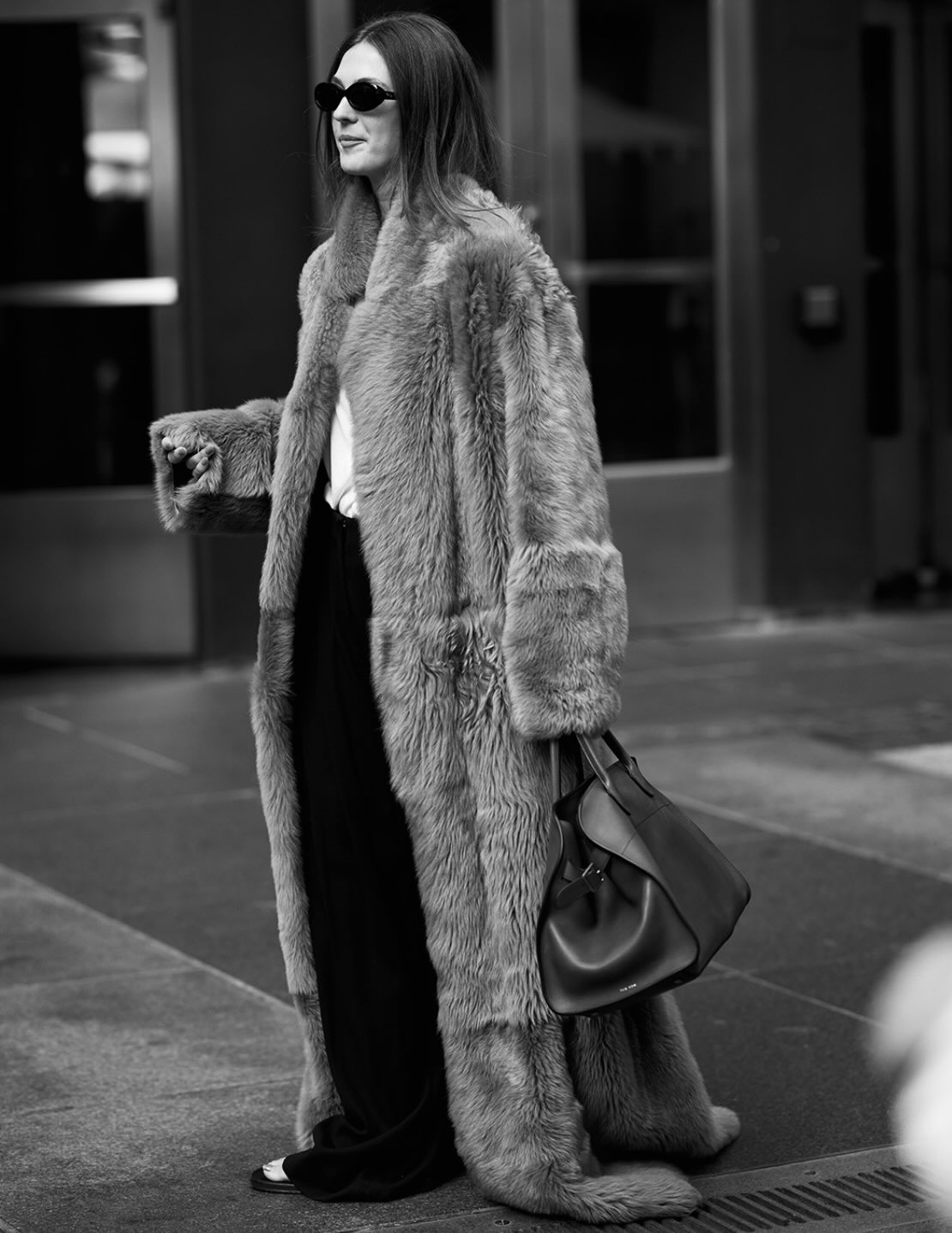 Street style photo of woman wearing a long fur coat.