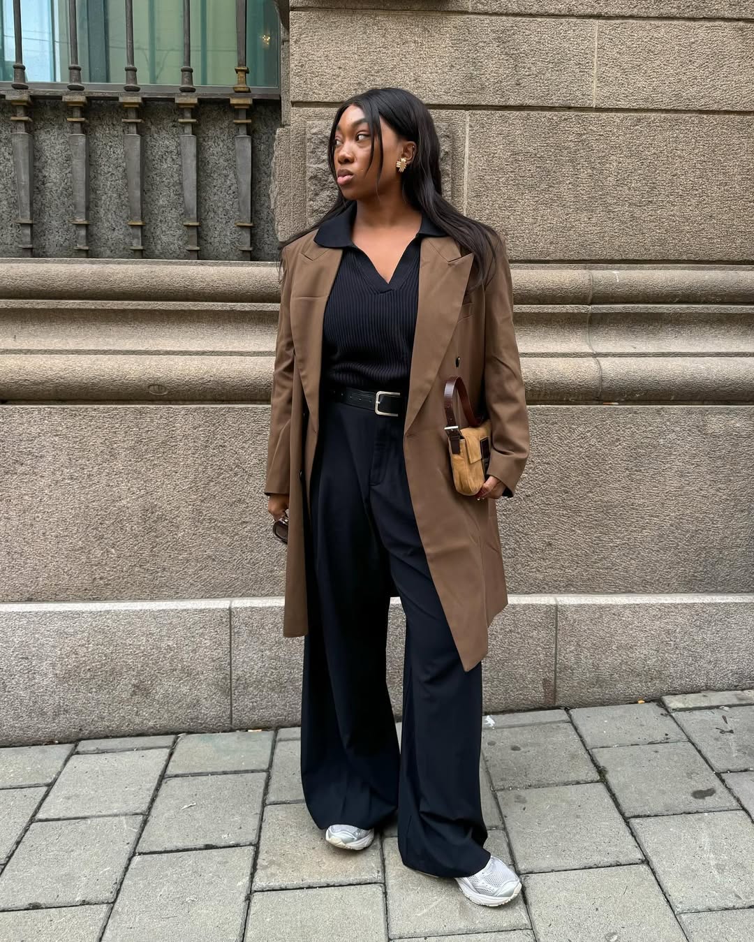 Influencer Nnenna Echem in a brown jacket, black wide-leg pants, and white sneakers.