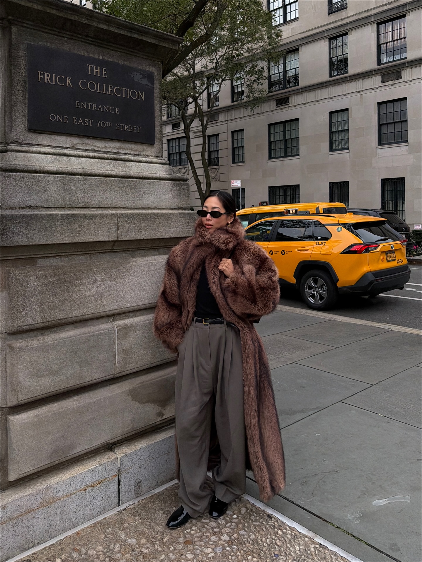 Street style photo of woman wearing a long fur coat.
