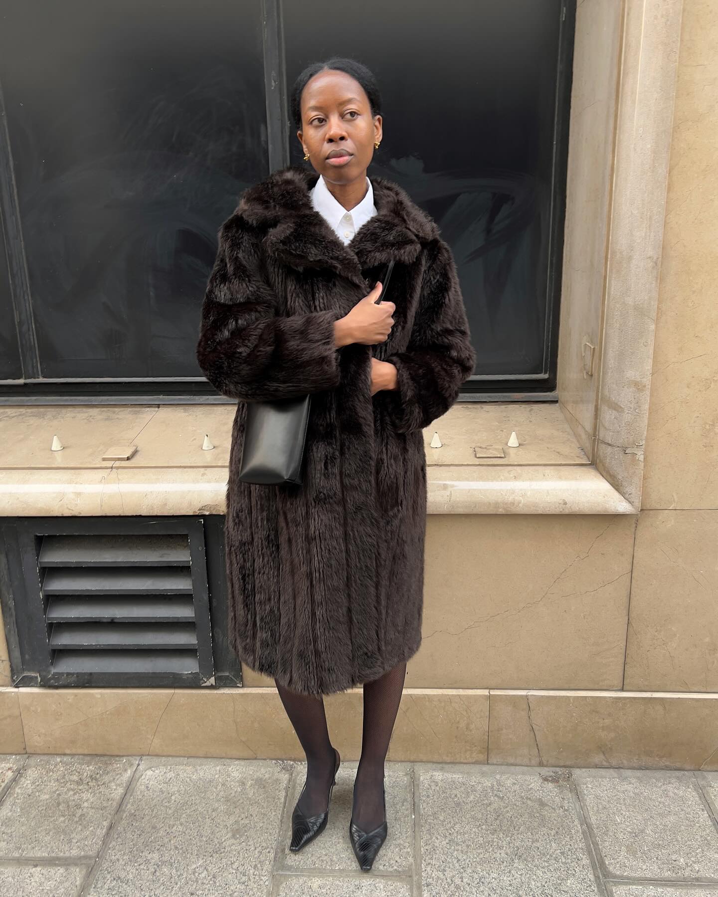 Street style photo of woman wearing a long fur coat.