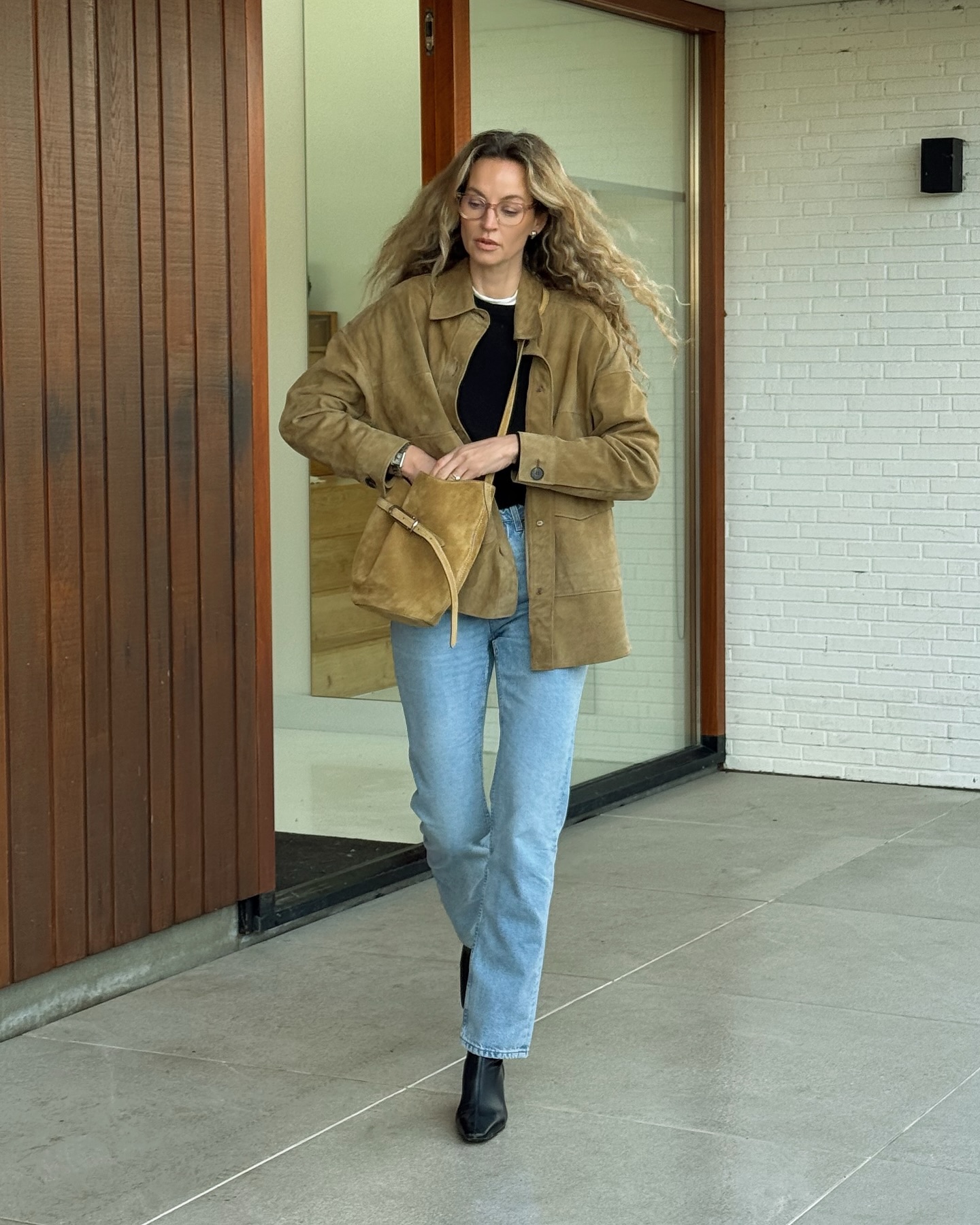 Woman wearing a suede jacket and jeans.