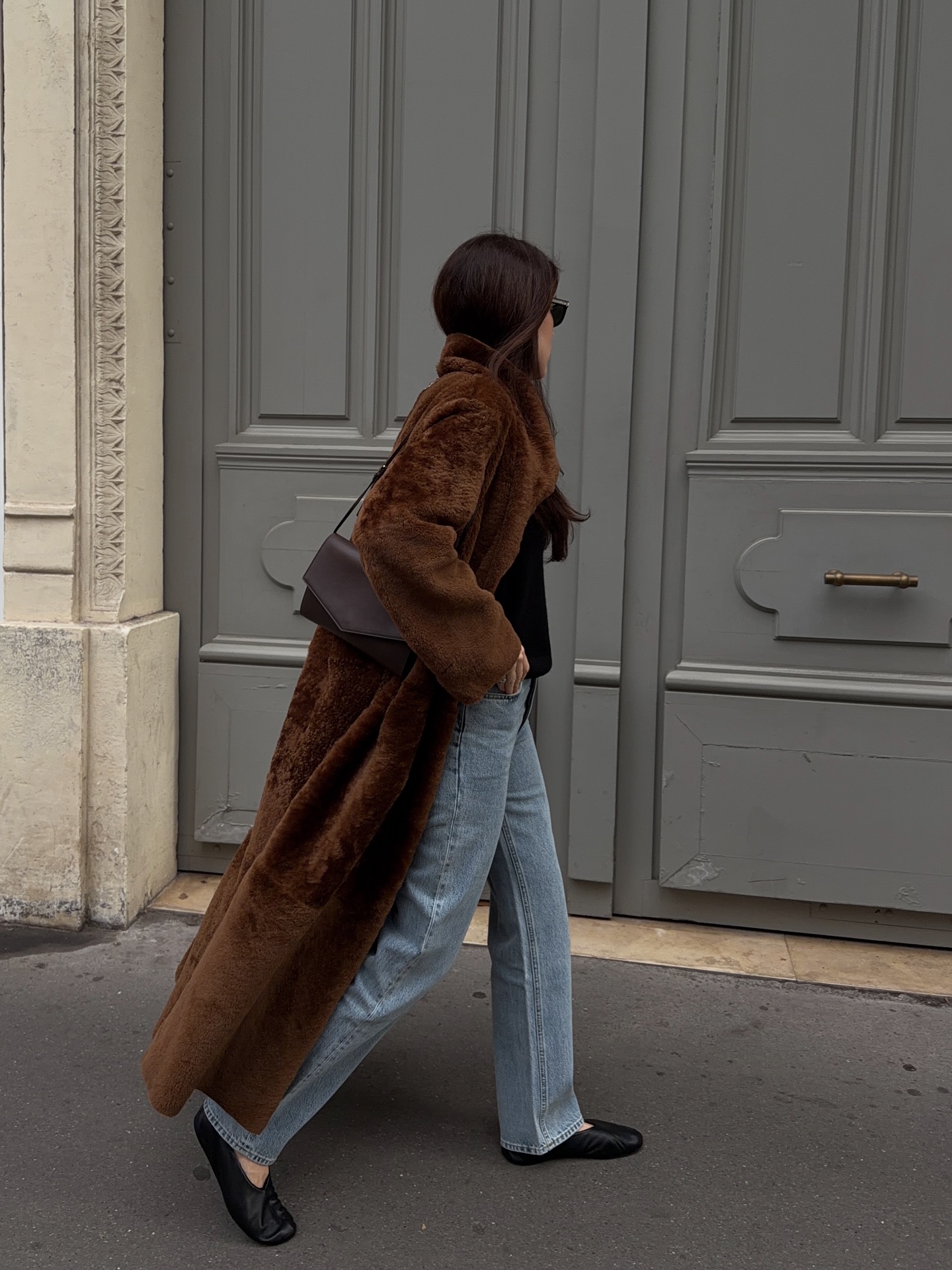 Street style photo of woman wearing a long fur coat.