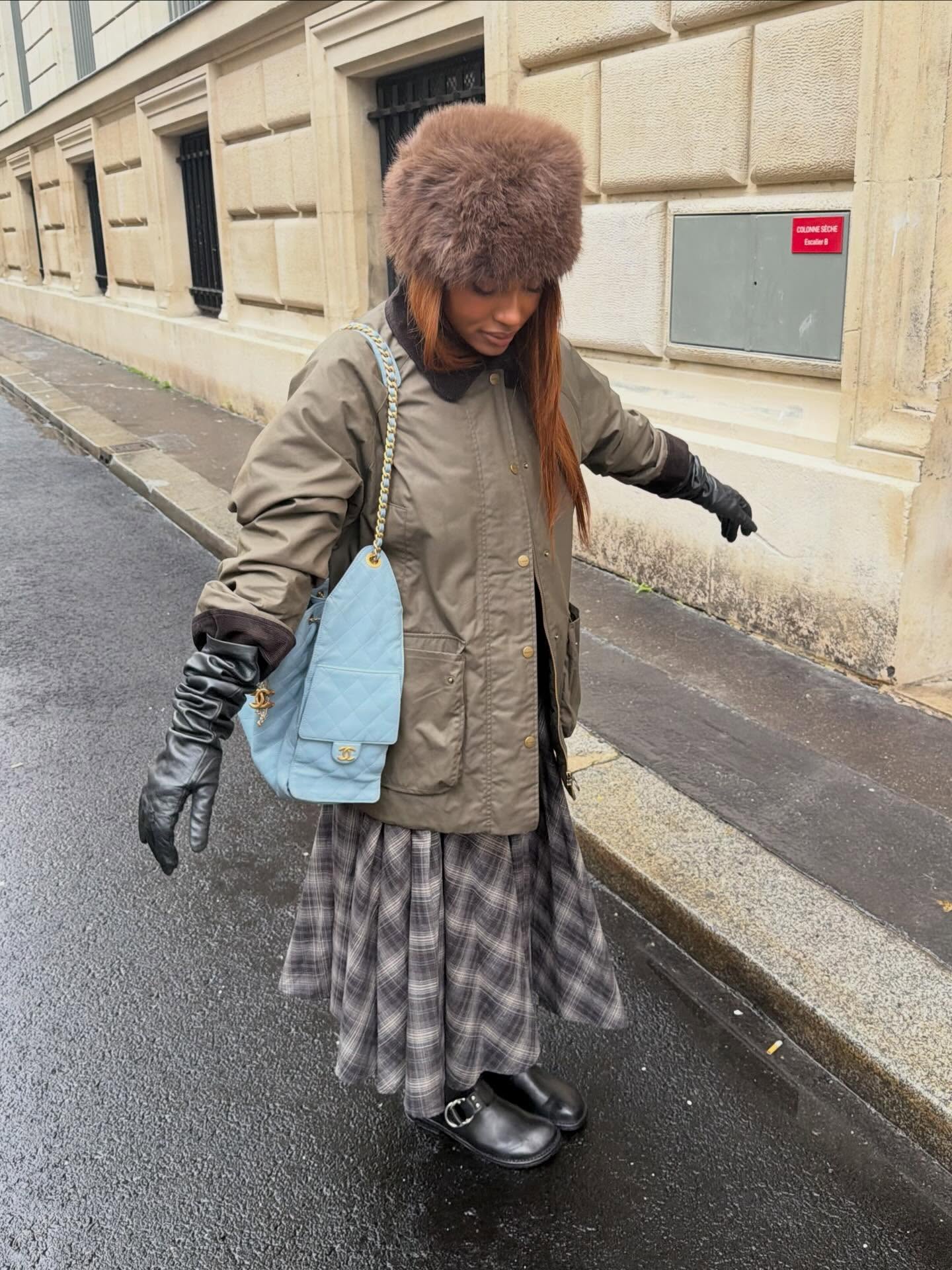 @mv.tiangue in a barn coat, a plaid skirt, leather gloves, and the faux-fur hat trend.