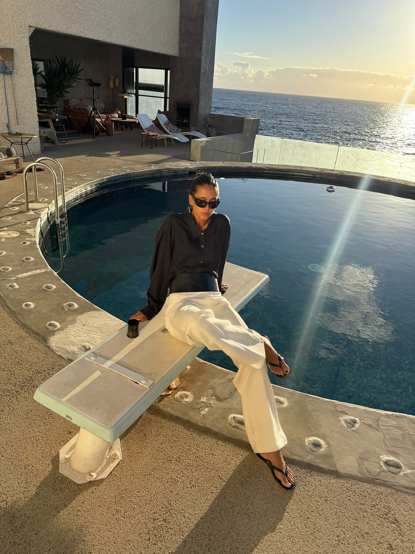 Woman sitting by a pool wearing flip-flops.