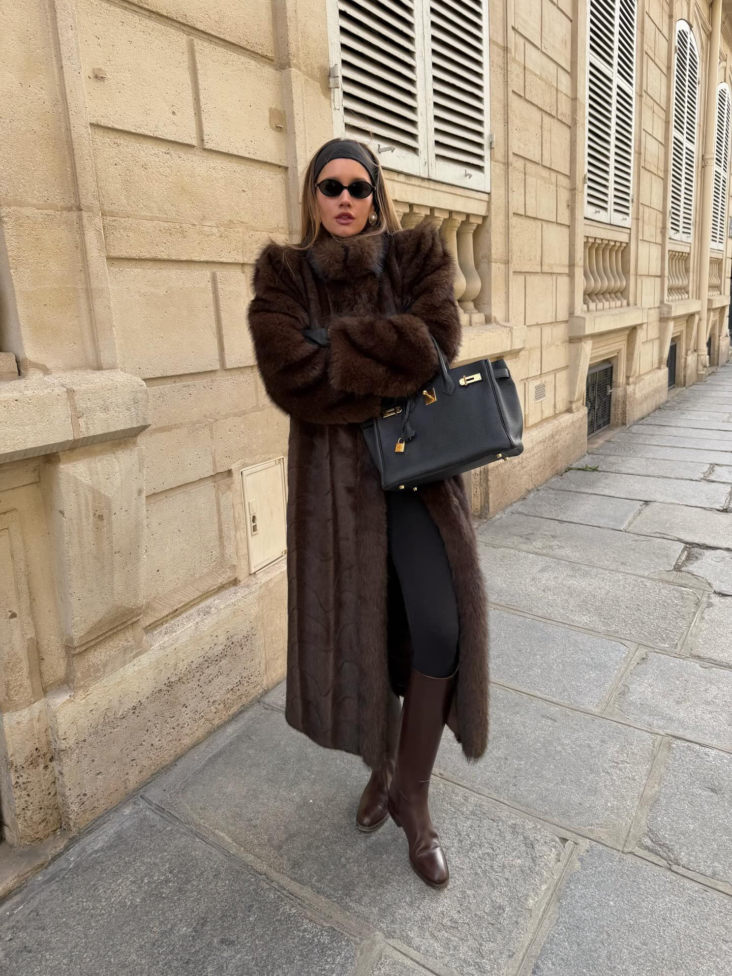 Street style photo of woman wearing a long fur coat.