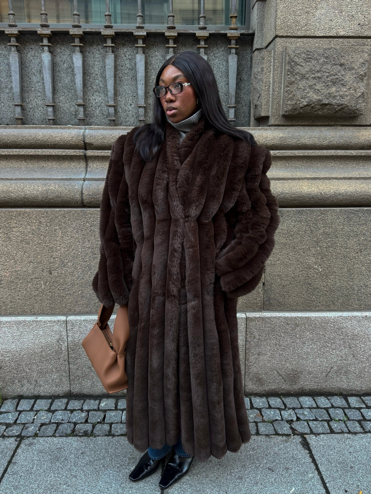 Street style photo of woman wearing a long fur coat.